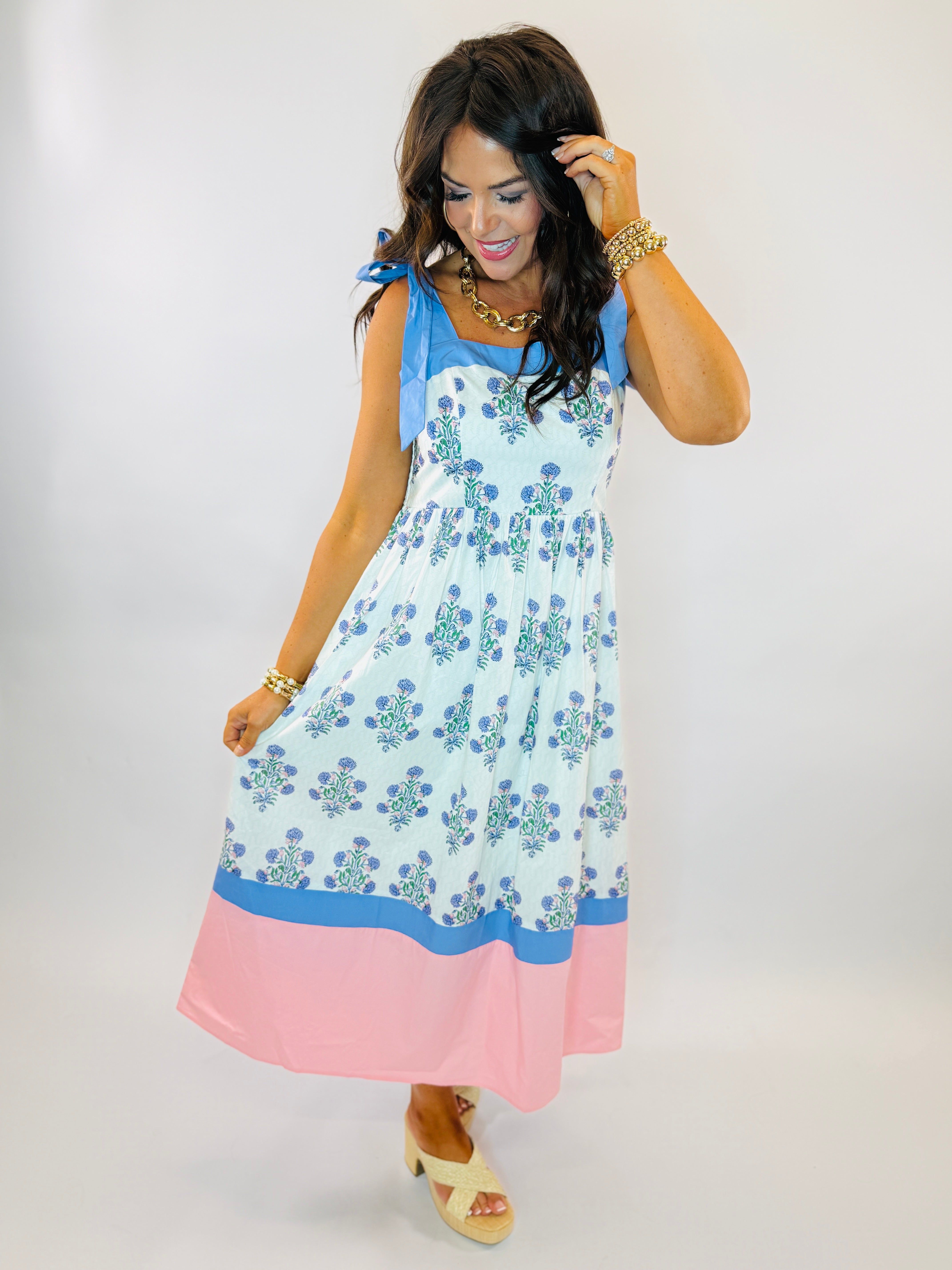 Woman wearing Jackie Dress with blue floral print, pink hem detail, and blue shoulder ties