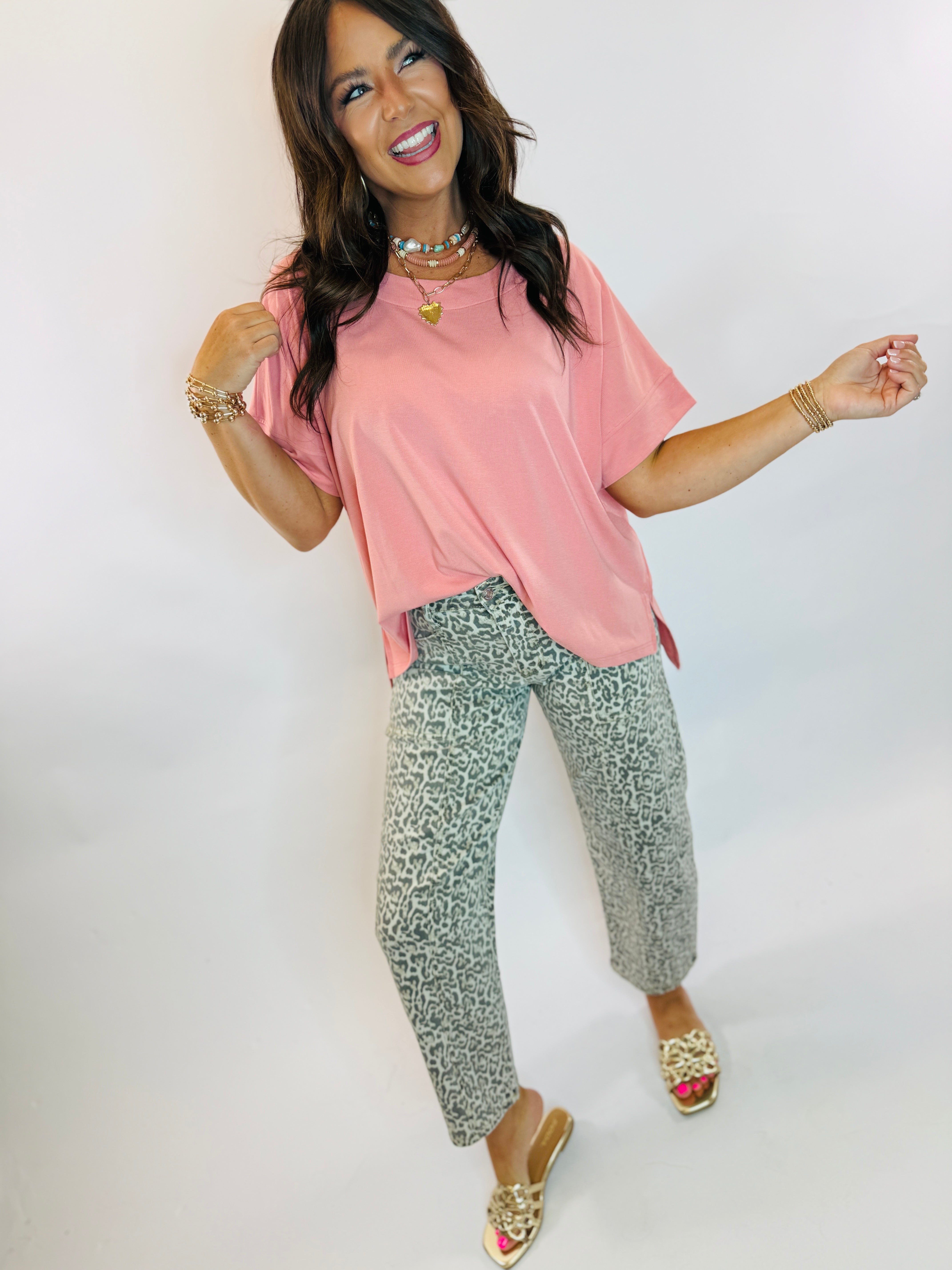 Woman wearing gray leopard print barrel-leg crop denim jeans paired with a pink top and gold sandals.