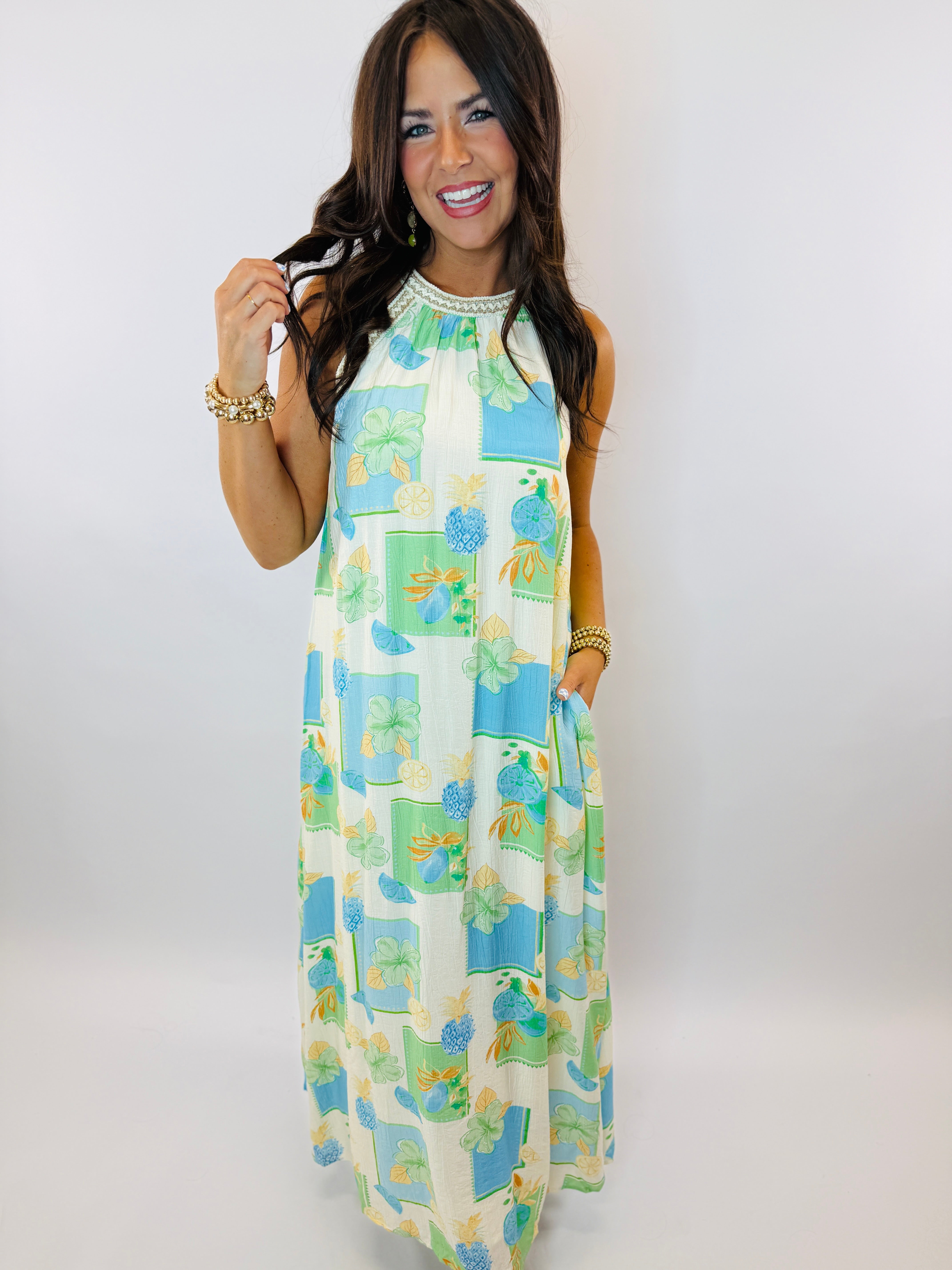Woman wearing colorful sleeveless Bermuda maxi dress with tropical floral print and embellished neckline