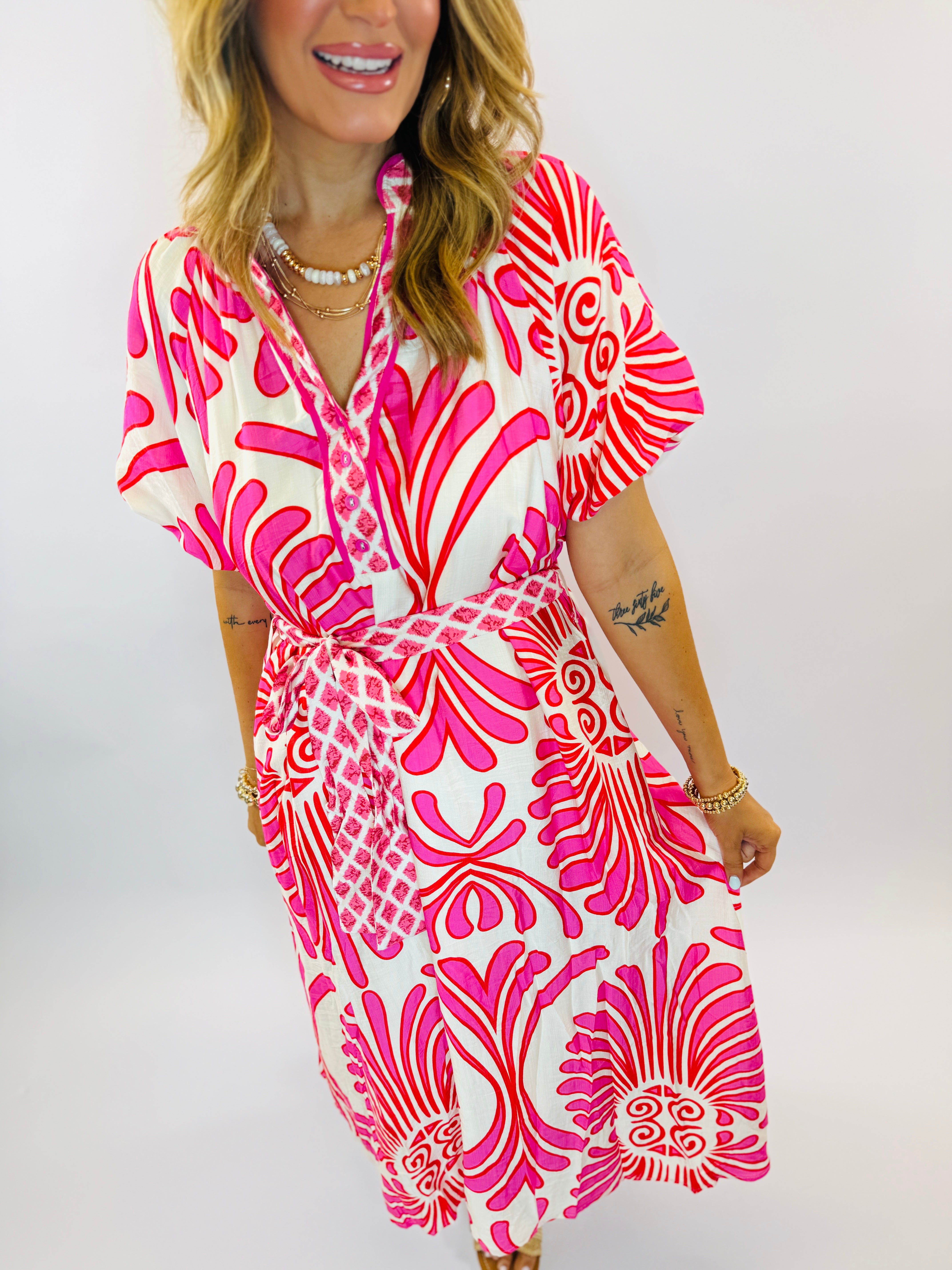 Woman wearing pink and white patterned wrap dress with short sleeves and tie waist detail