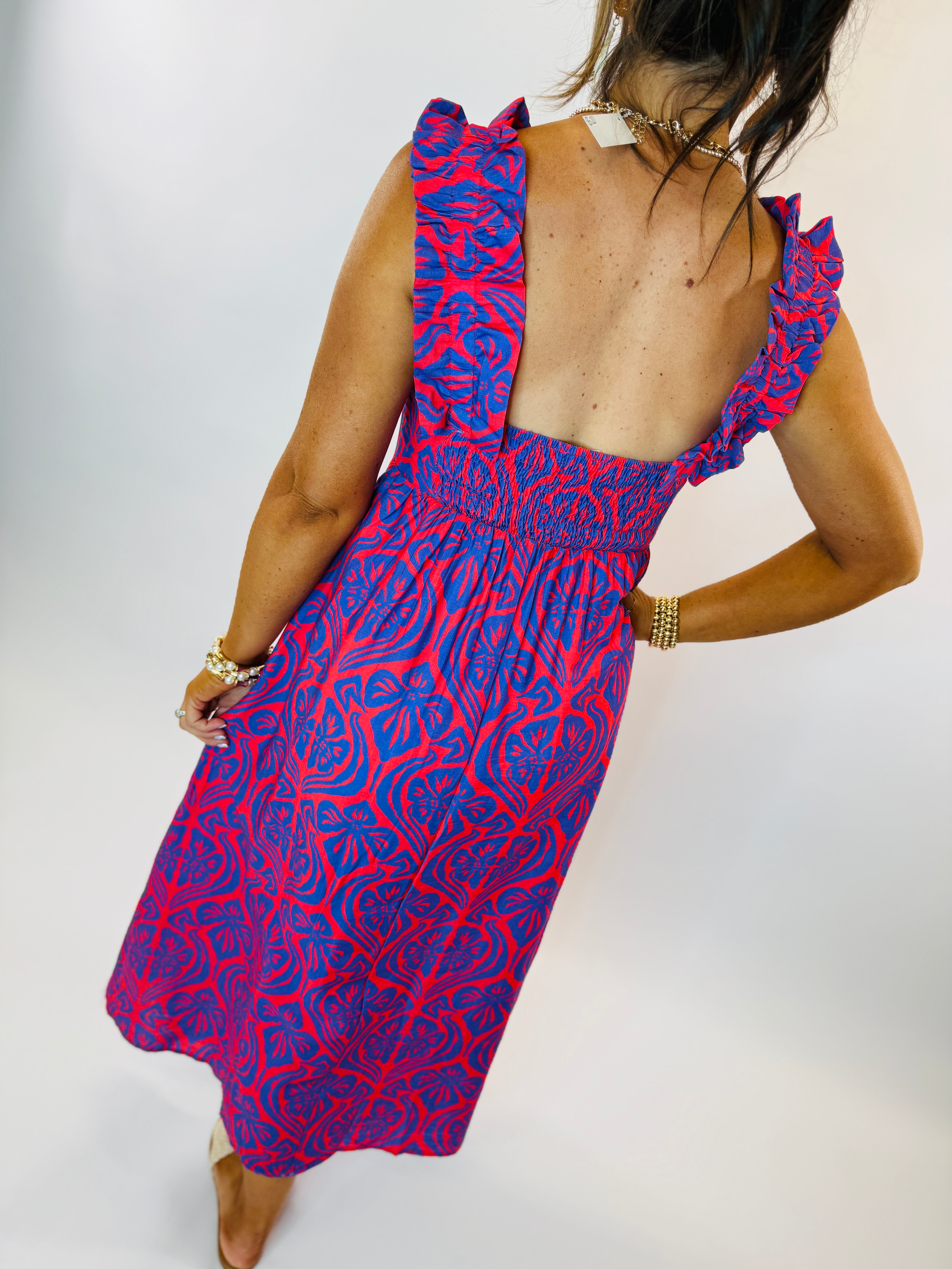 Woman wearing red and blue patterned Ciara dress with ruffled straps and open back detail.