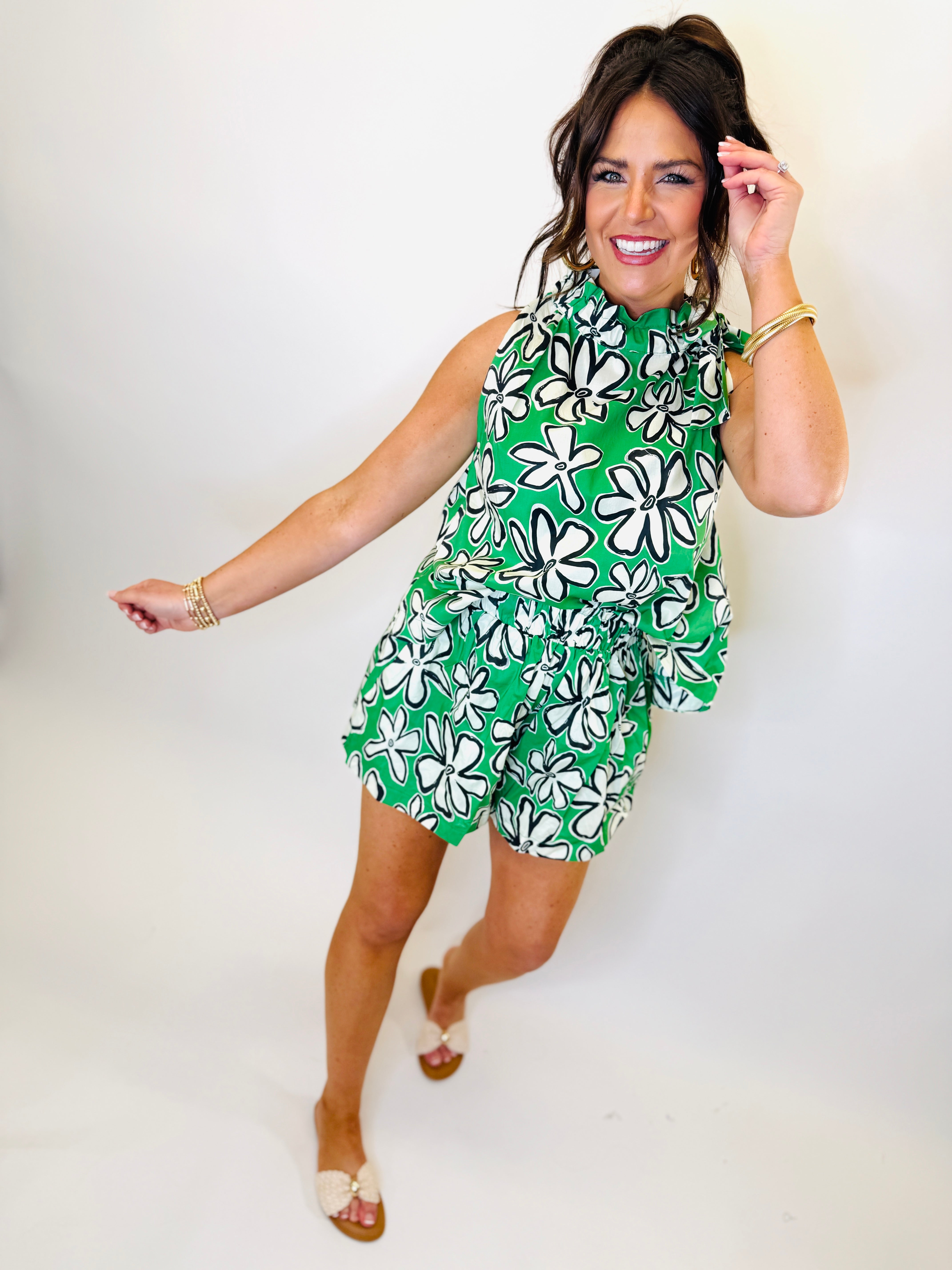 Woman wearing green floral print sleeveless top and matching shorts set with white flowers pattern