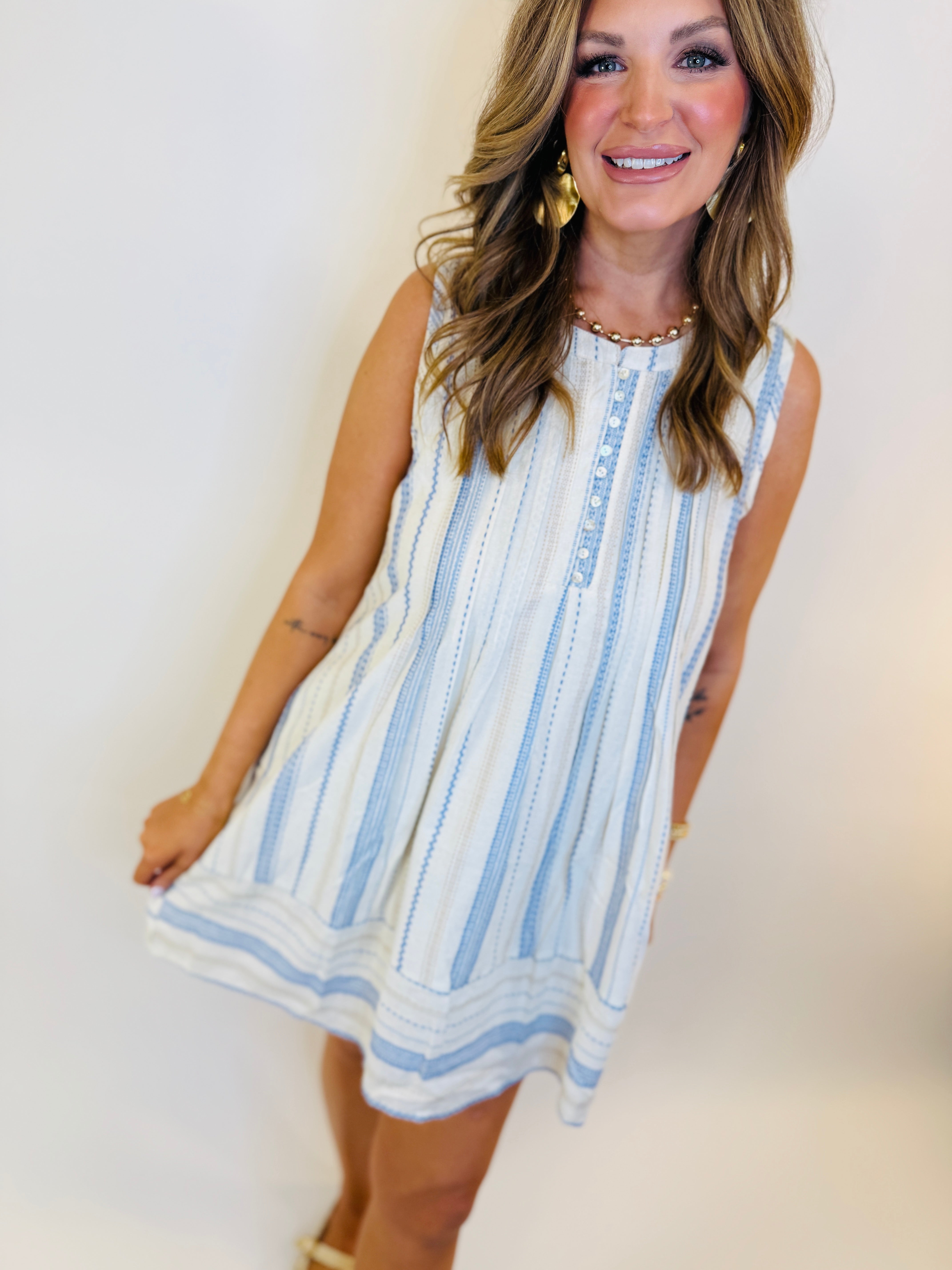 Woman wearing white sleeveless dress with blue vertical stripes and lace trim details