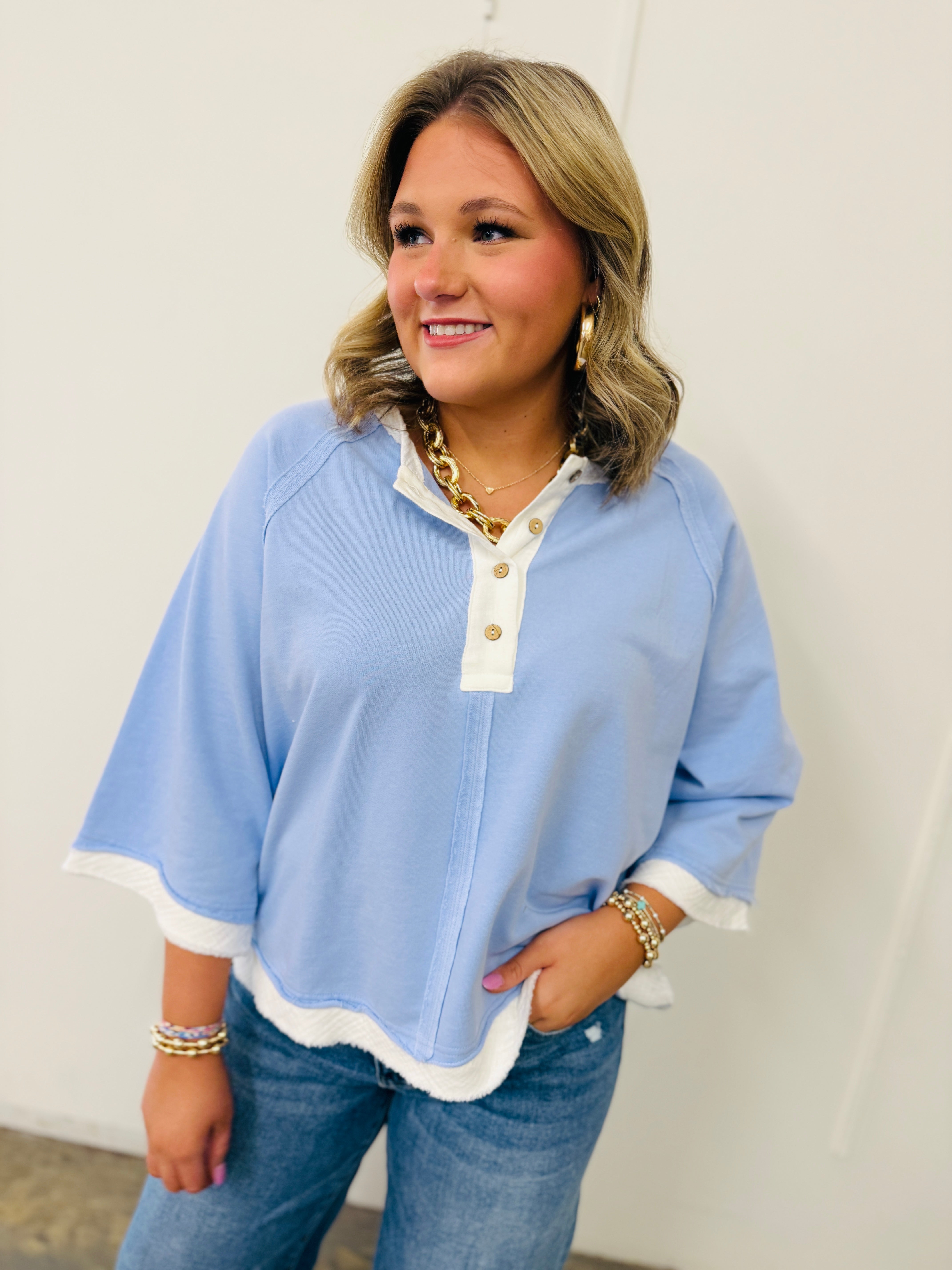 Woman wearing light blue Elizabeth top with white contrast trim and button details, paired with jeans.