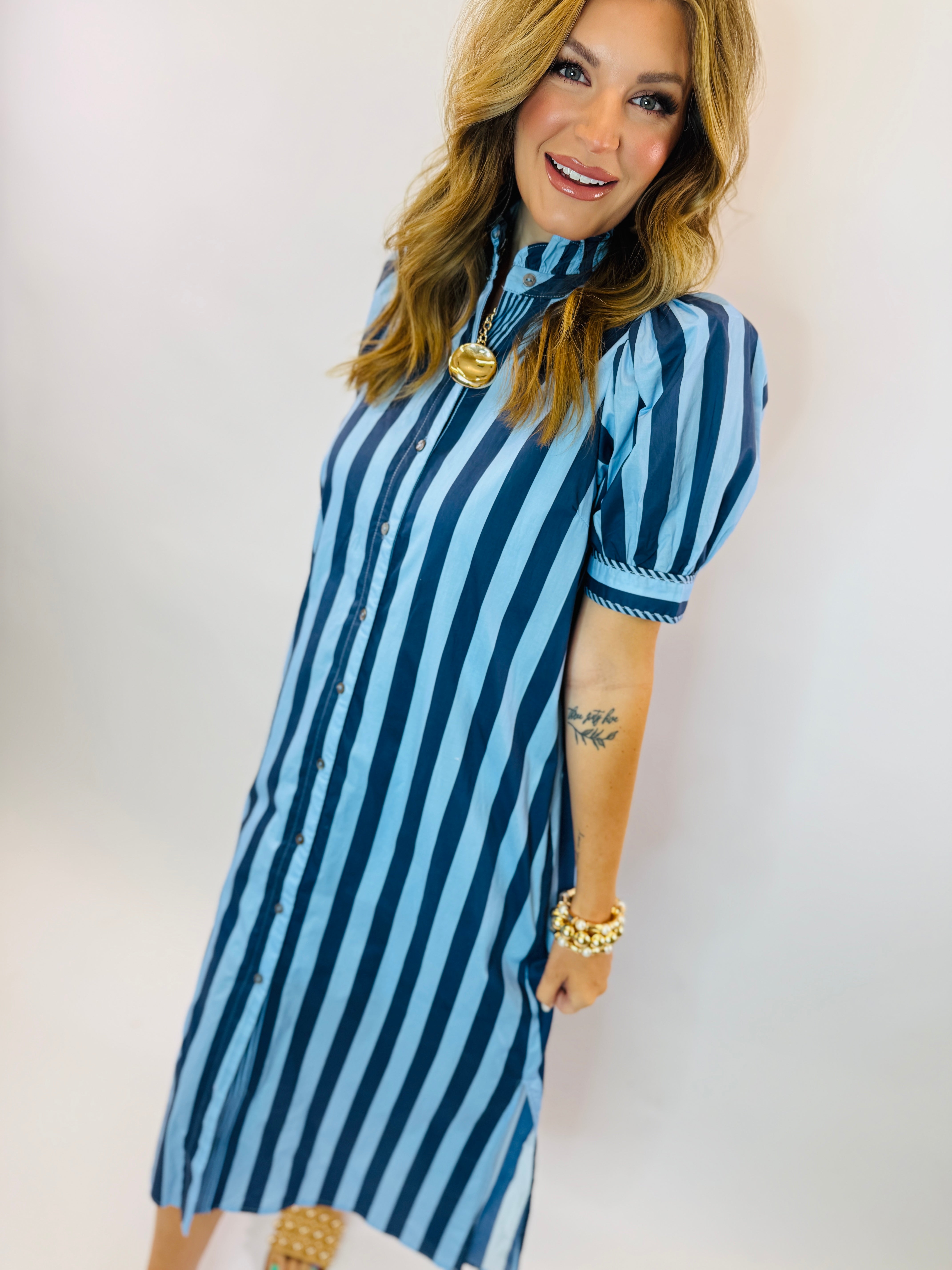 Woman wearing blue and white striped button-up maxi dress with short sleeves and high neckline