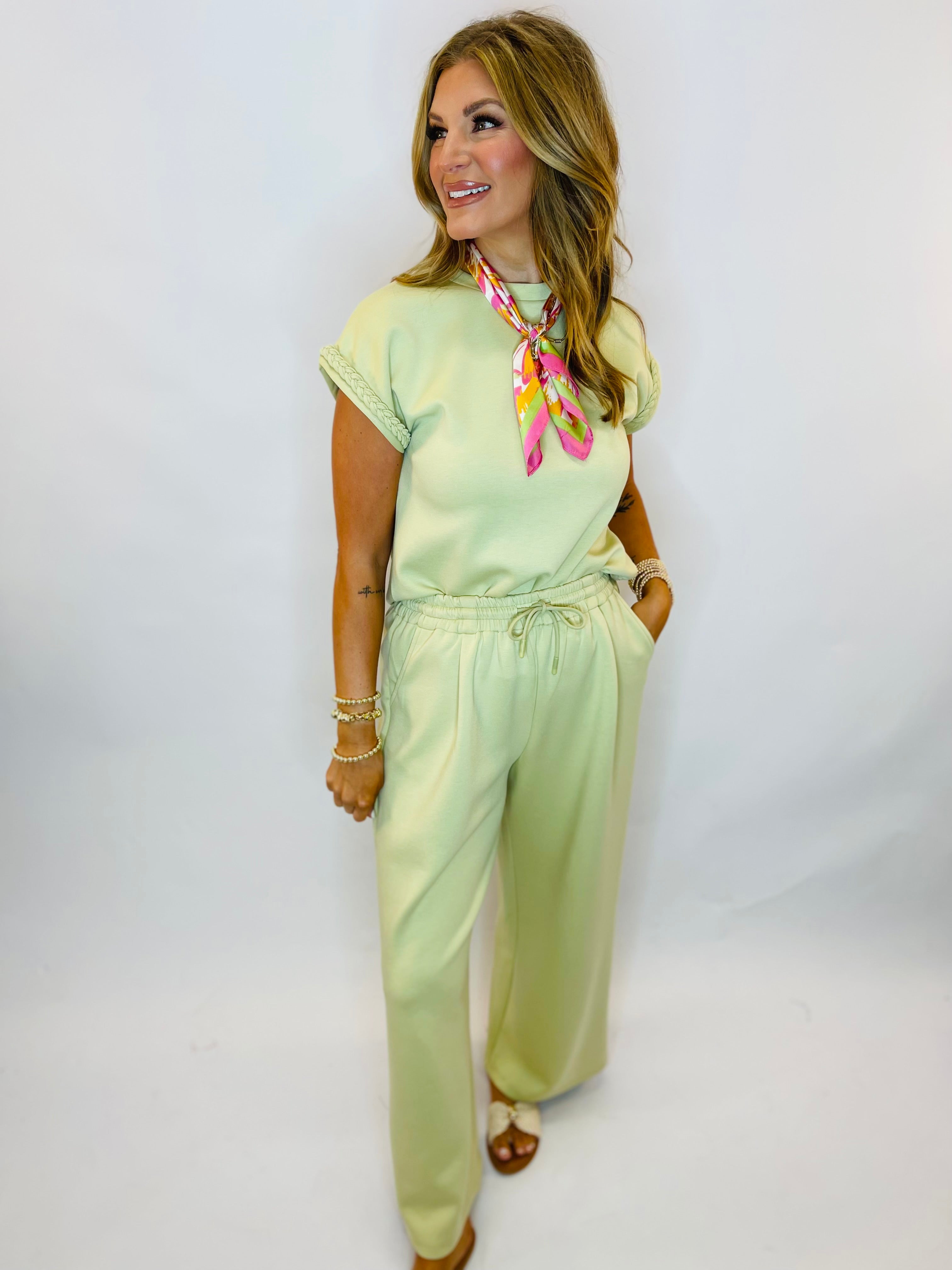 Woman wearing a mint green short-sleeve top with braided sleeve detail and matching drawstring pants set.