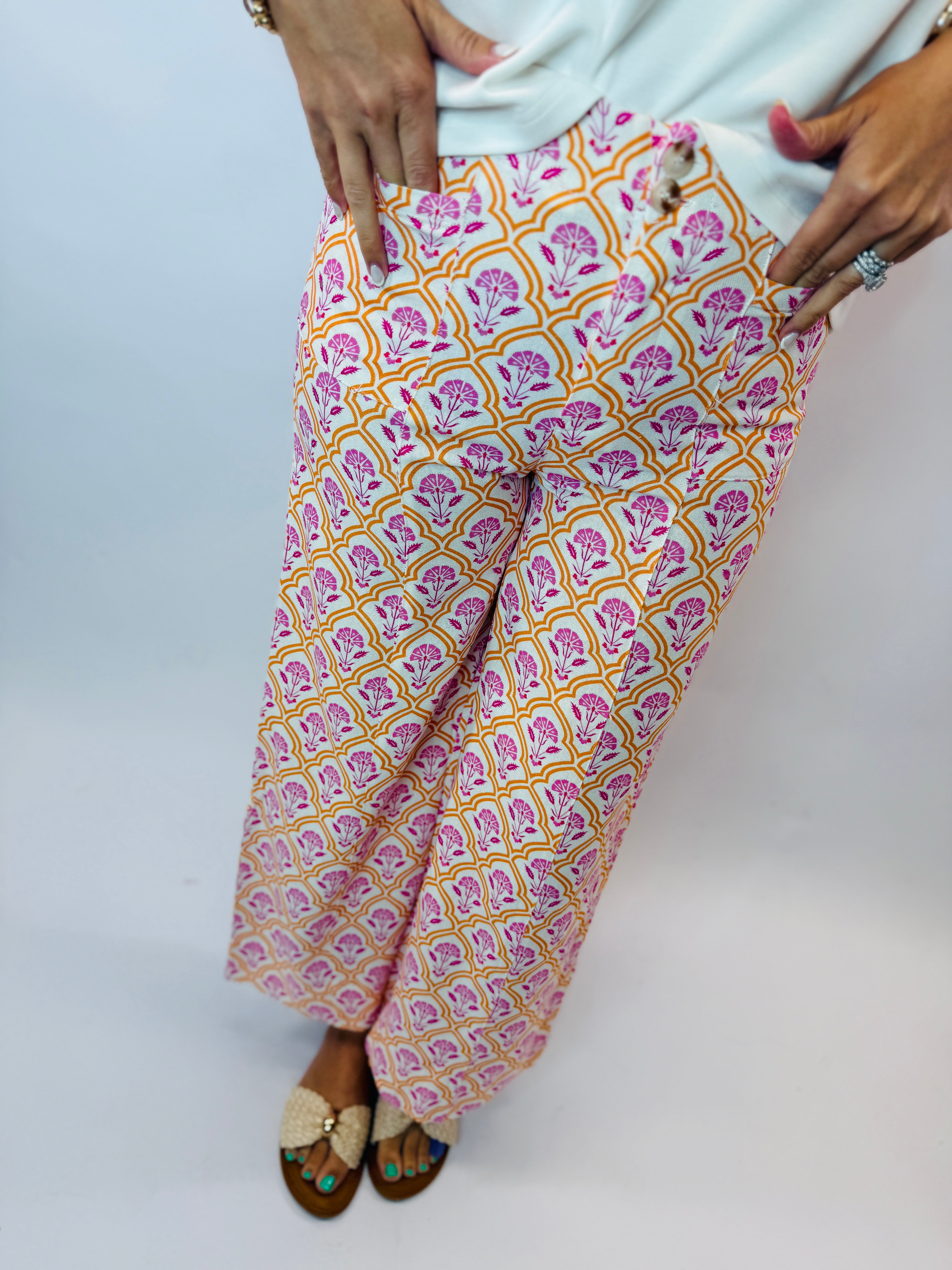 Woman wearing colorful patterned Camille pants with pink and orange floral print, paired with sandals