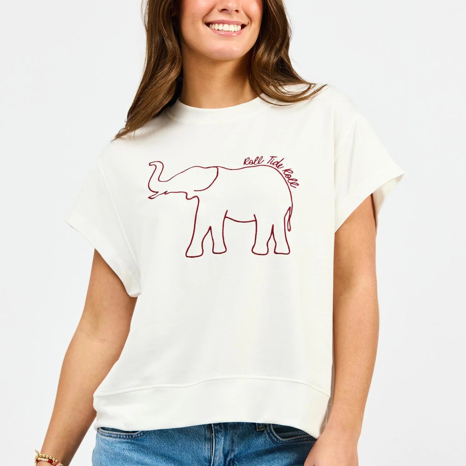 White short-sleeve top with crimson embroidered elephant outline and "Roll Tide Roll" script graphic.