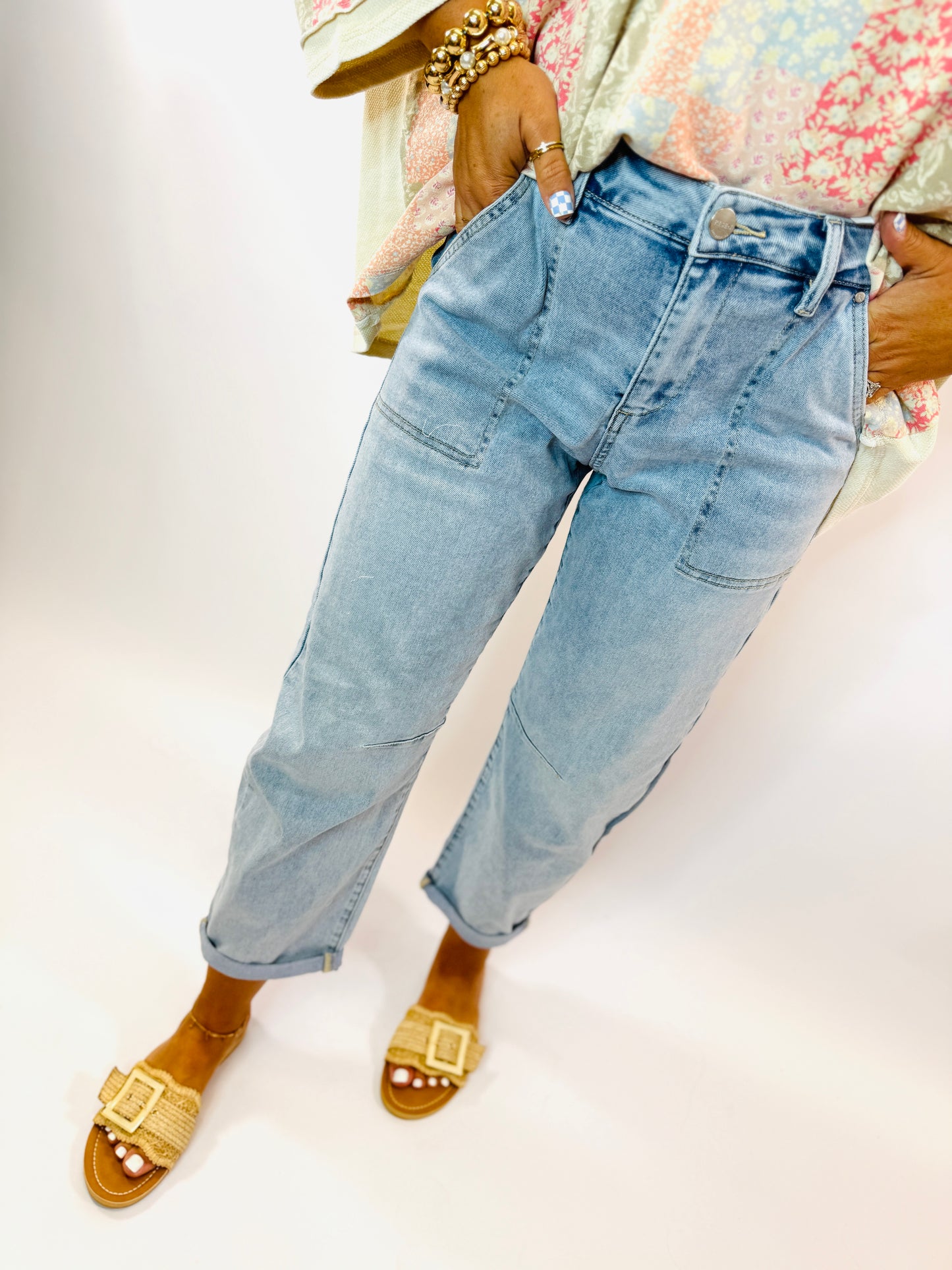 Woman wearing light blue relaxed-fit Soleil jeans with rolled cuffs, paired with gold woven sandals and beaded bracelets.