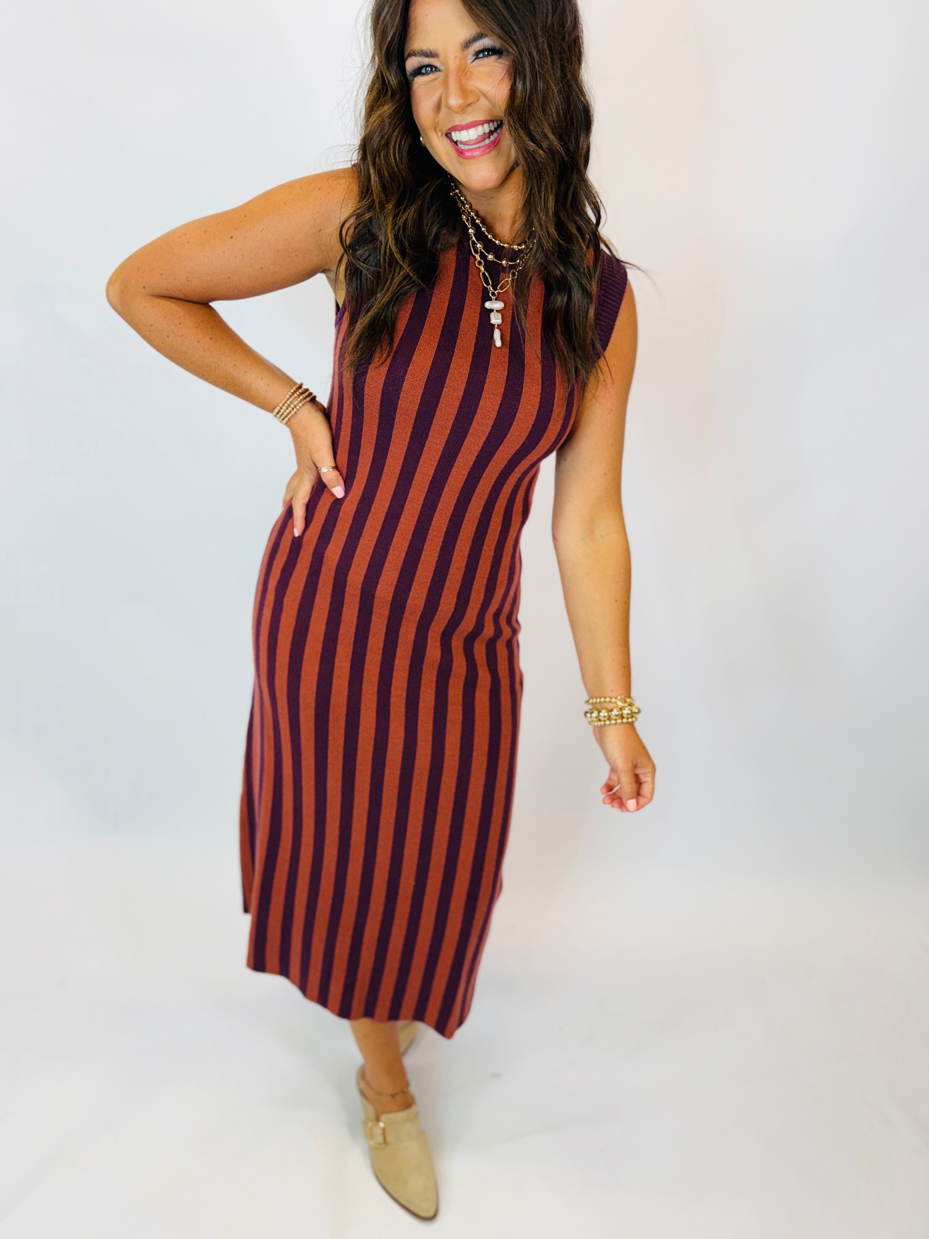 Darcy Dress in burgundy and rust vertical stripes, sleeveless midi length, styled with gold jewelry and tan mules.