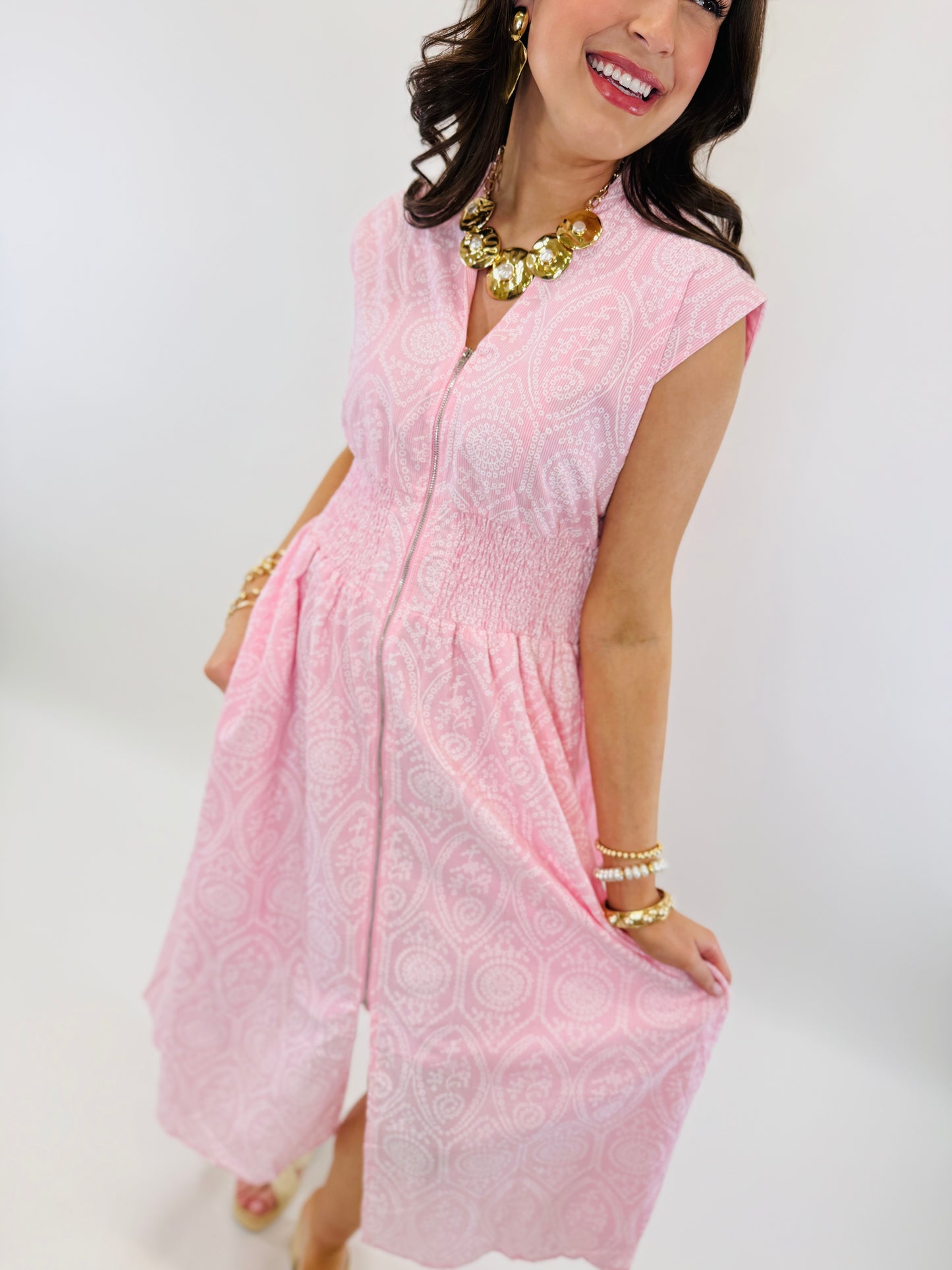 Woman wearing pink paisley print midi dress with cap sleeves, smocked waist, and button-front closure