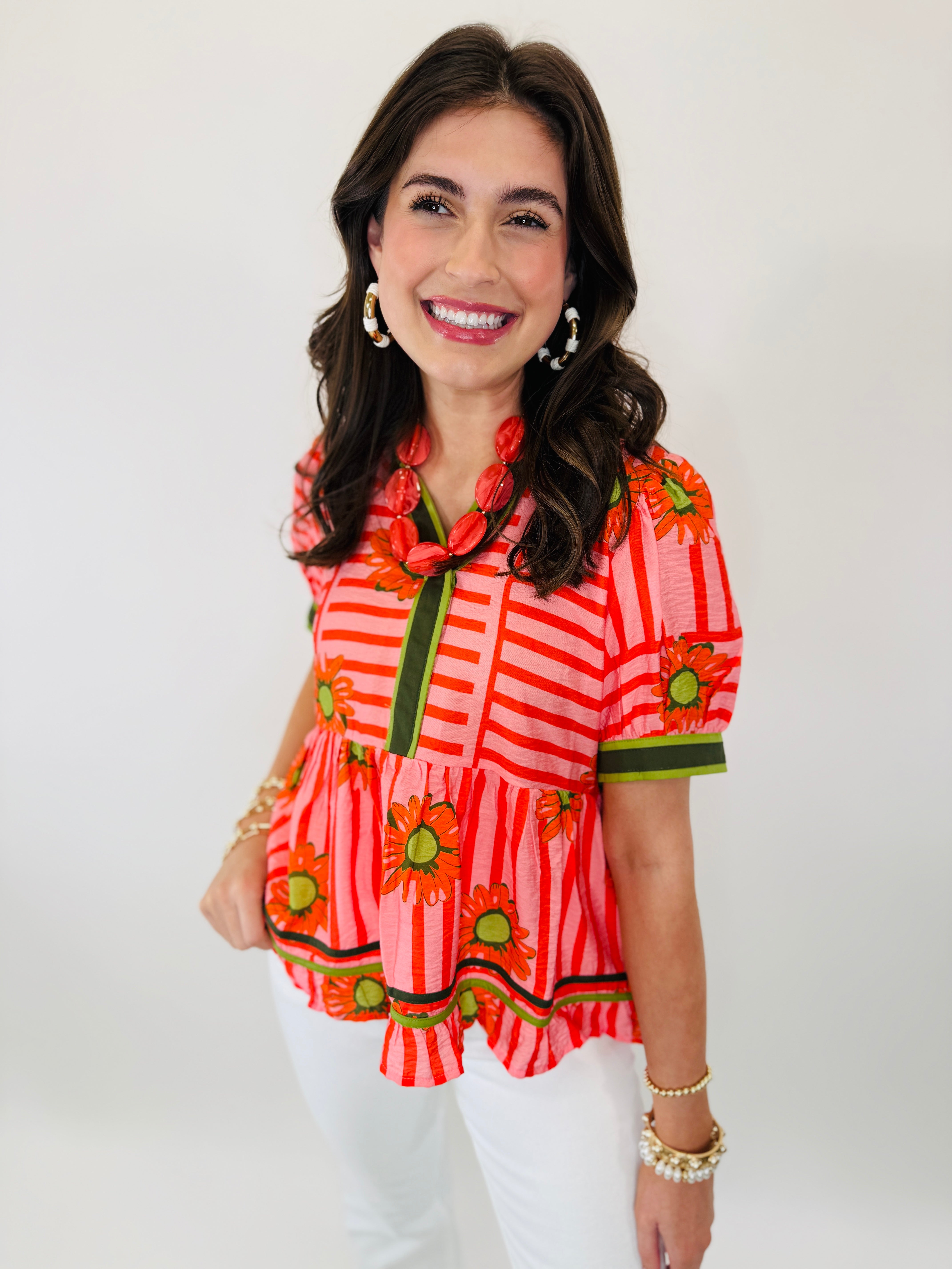 Woman wearing colorful striped Billie top with orange sunflower print and green ribbon ties