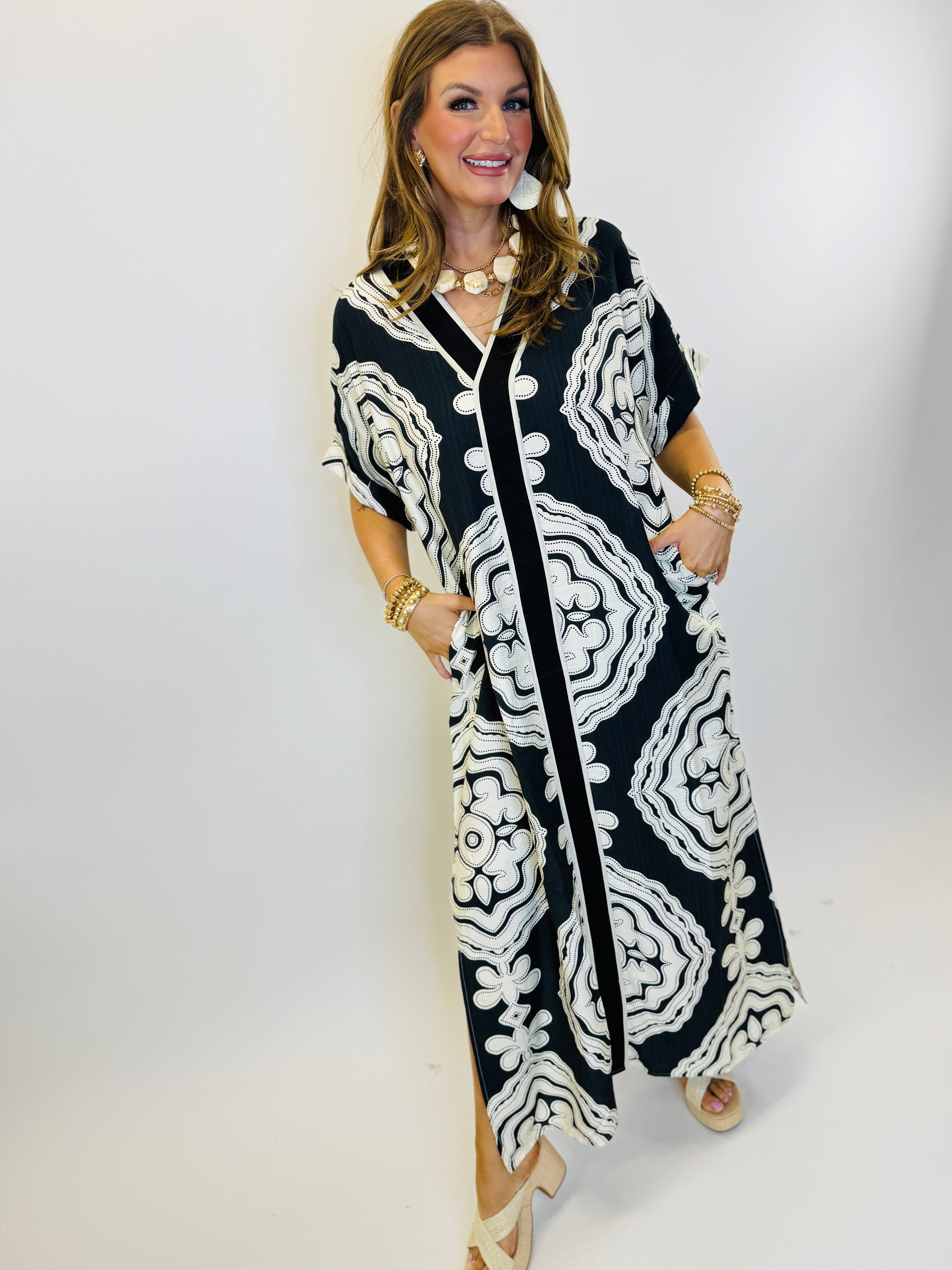 Woman wearing black and white paisley pattern maxi dress with gold jewelry and sandals