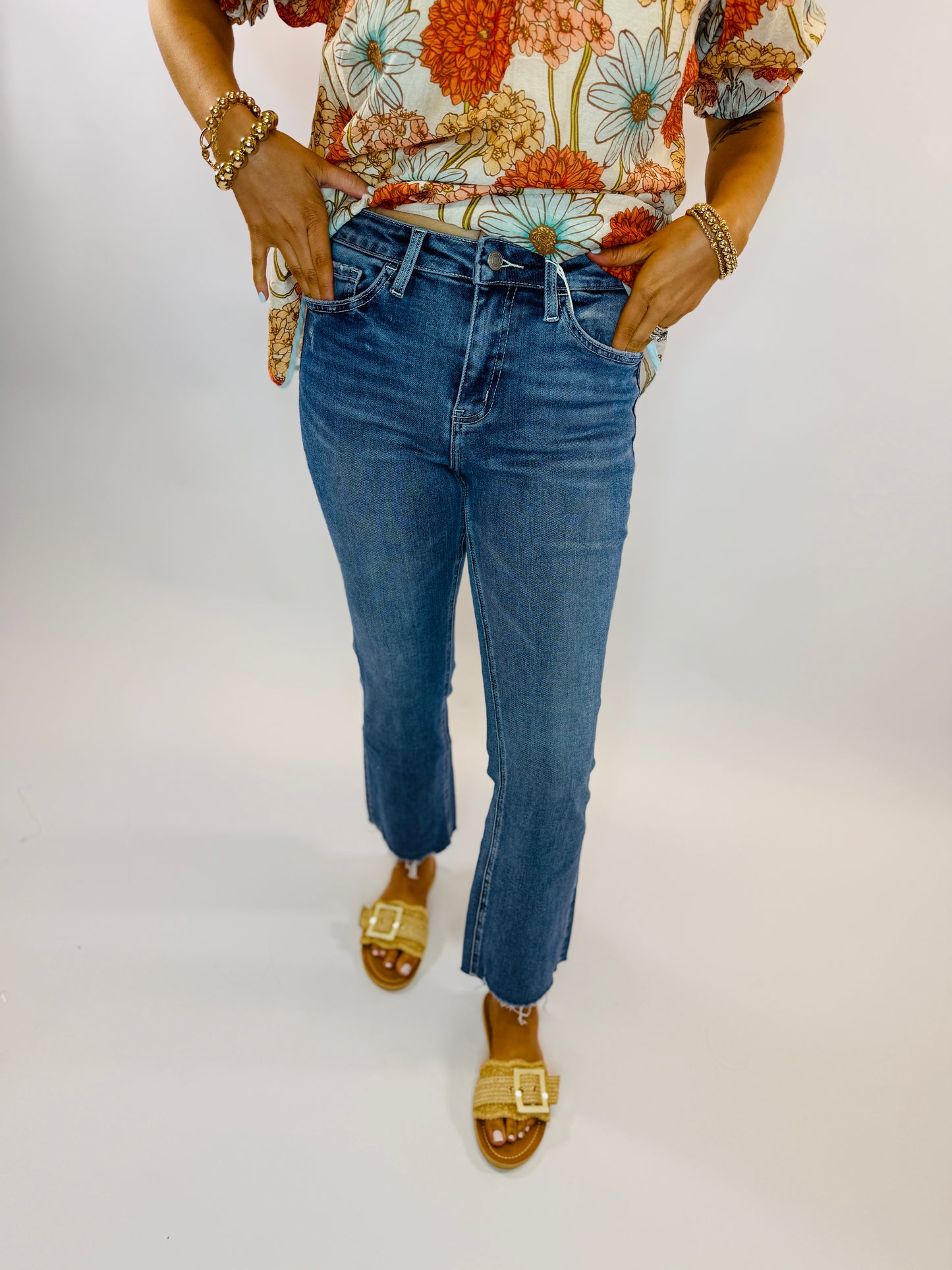 Woman wearing blue cropped straight-leg Jenna jeans with floral top and yellow sandals