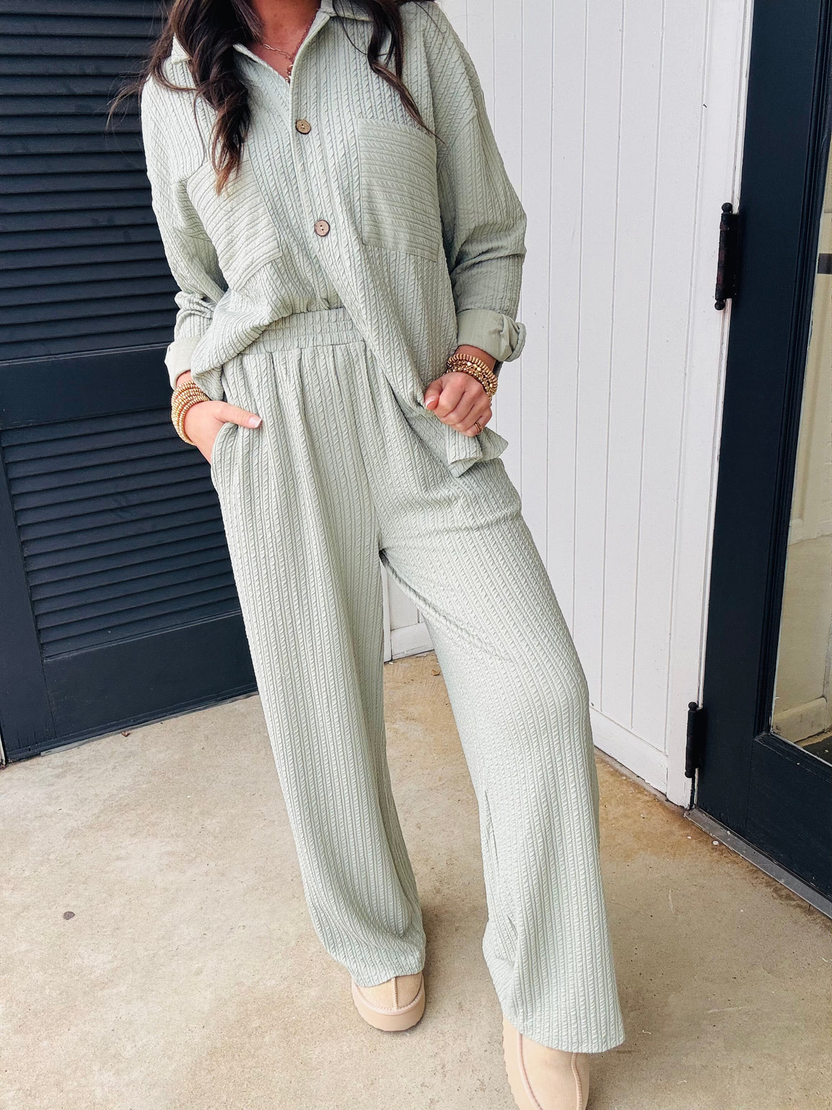 Woman wearing sage green ribbed matching set with button-up top and wide-leg pants, standing outdoors.