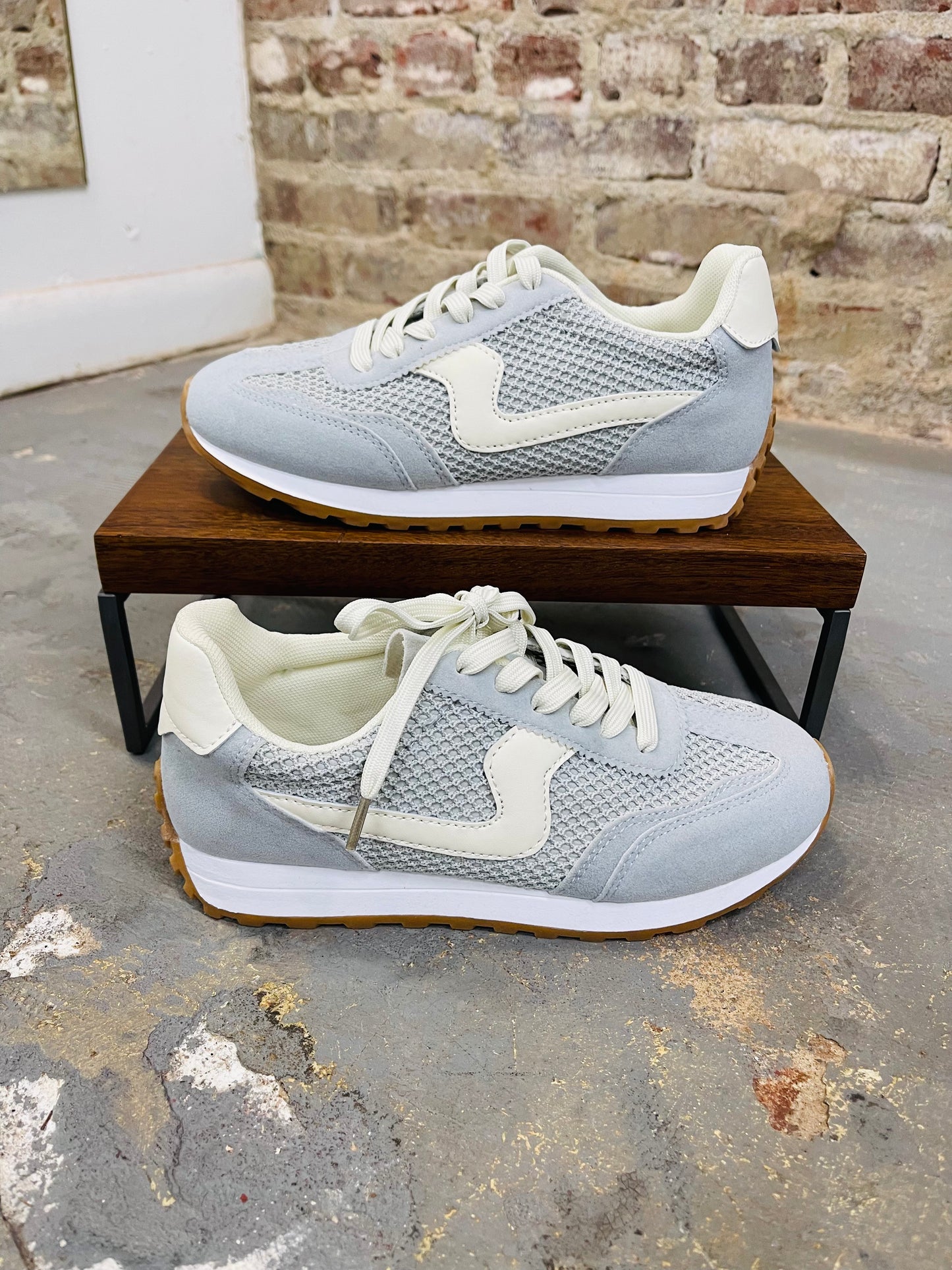 Light blue Griffin sneakers with white swoosh logo and gum sole displayed on wooden platform