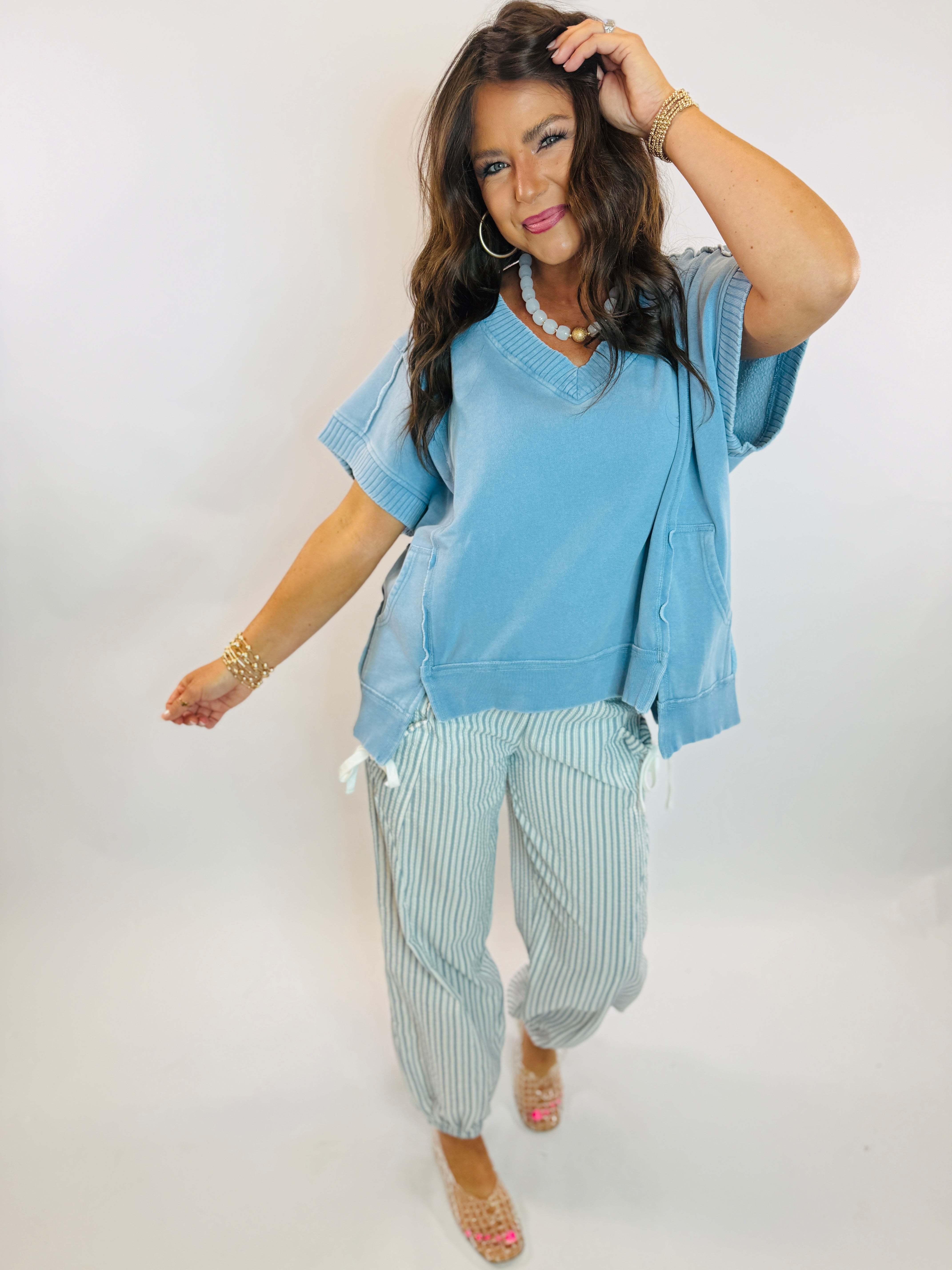 Polly Oversized V-neck short sleeve blue top paired with striped cropped pants on brunette model.