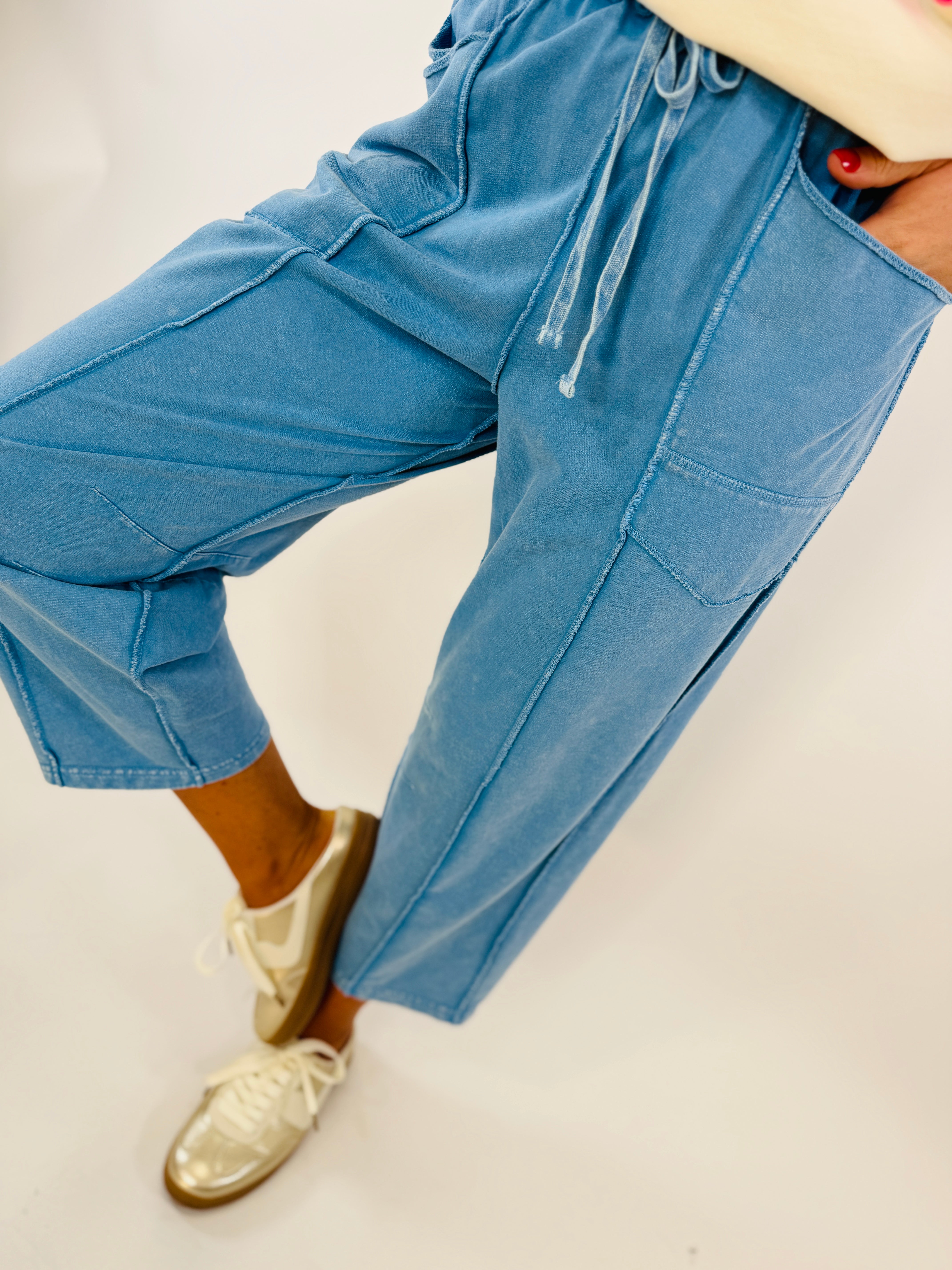 Blue wide leg pants with cargo pockets and drawstring waist, worn with cream sneakers