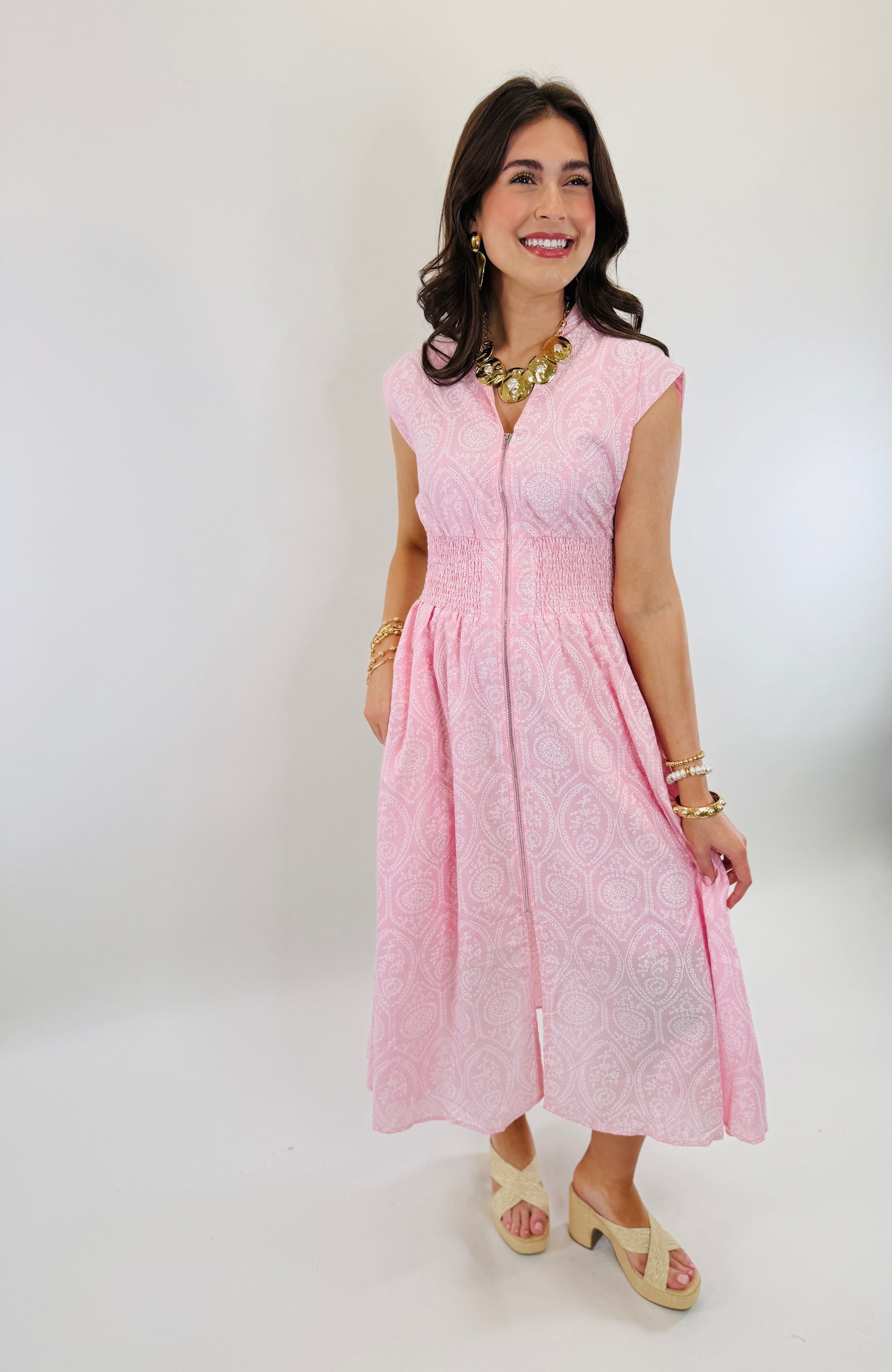 Woman wearing pink paisley patterned Kristine midi dress with cap sleeves and smocked waist detail