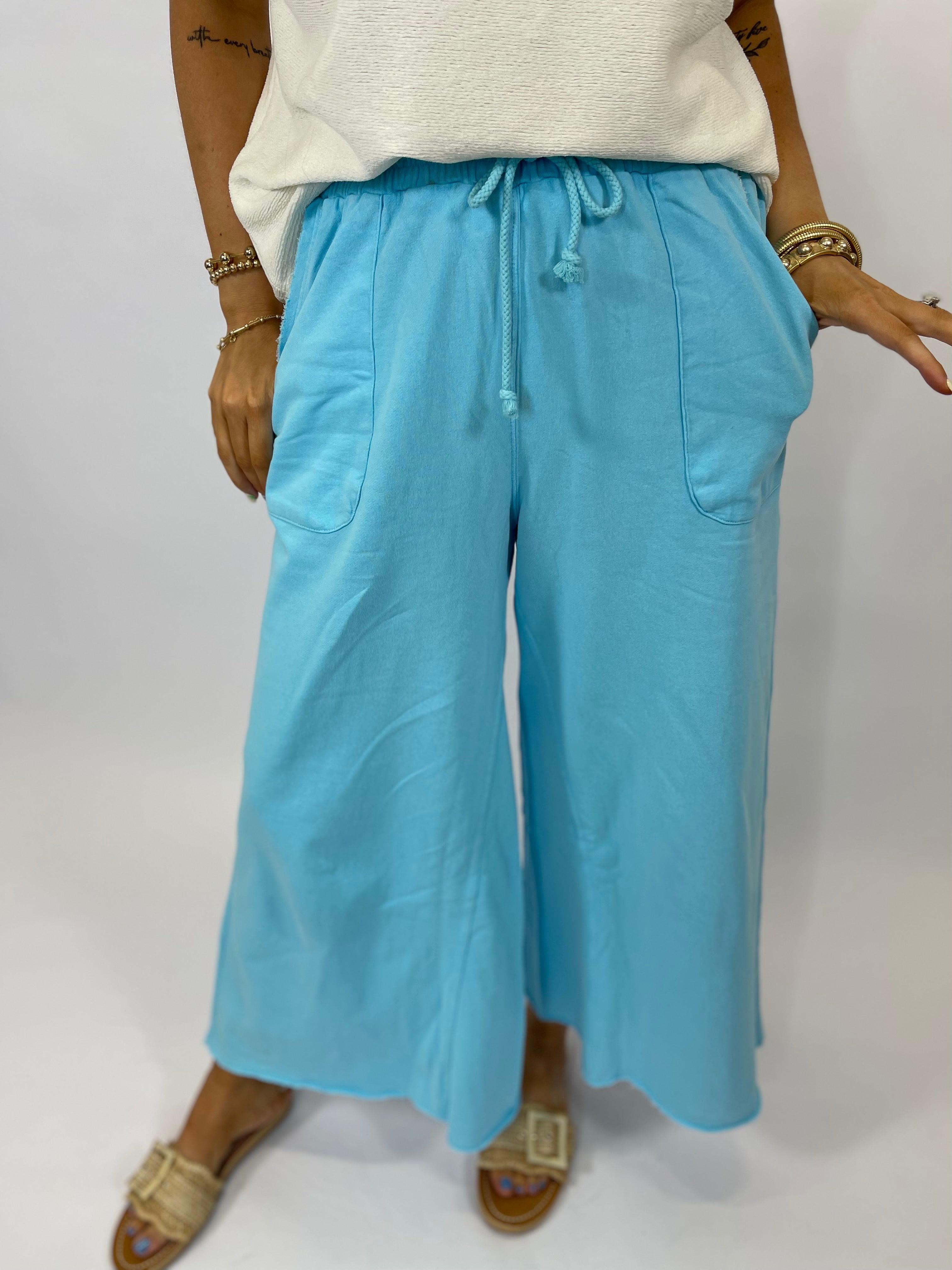 Light blue wide-leg drawstring pants with pockets, worn with white top and gold sandals