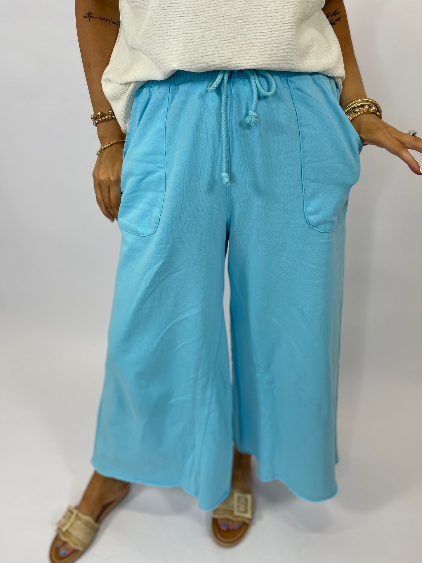 Light blue wide-leg drawstring pants with pockets, worn with white top and gold sandals