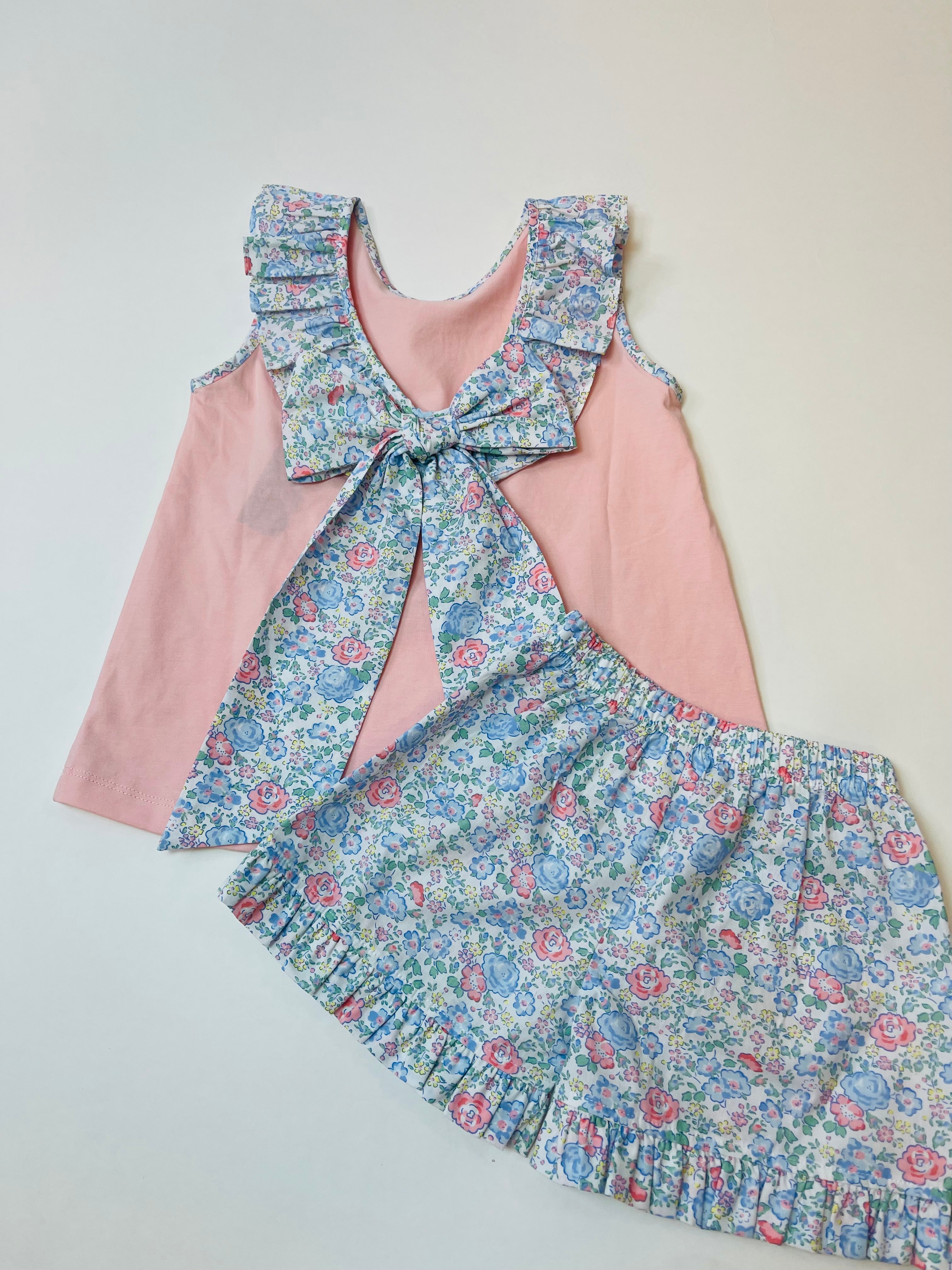 Pink sleeveless top with floral ruffle bow detail and matching floral shorts with ruffled hem.