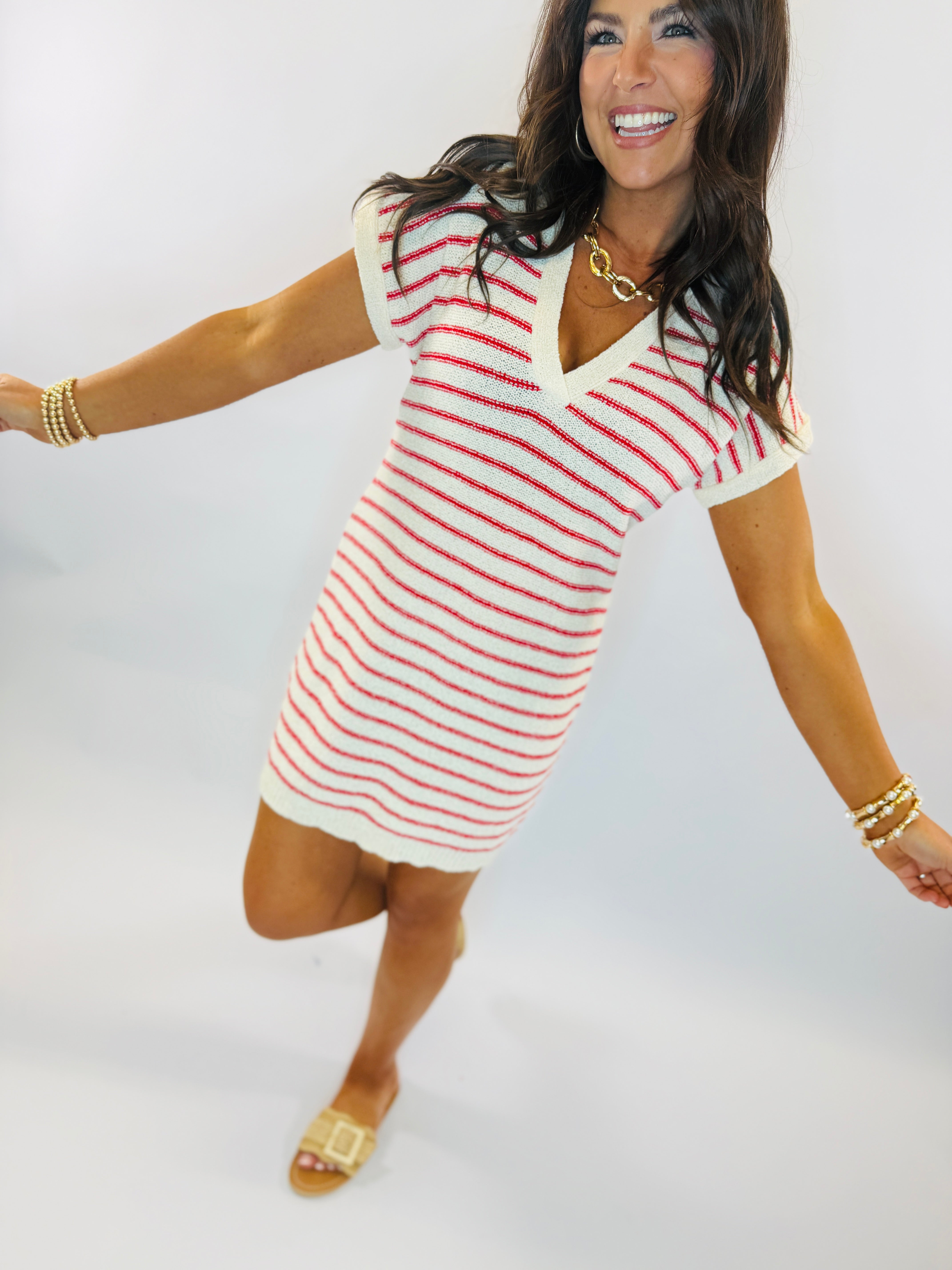 Woman wearing white and red striped short-sleeve mini dress with gold jewelry and sandals