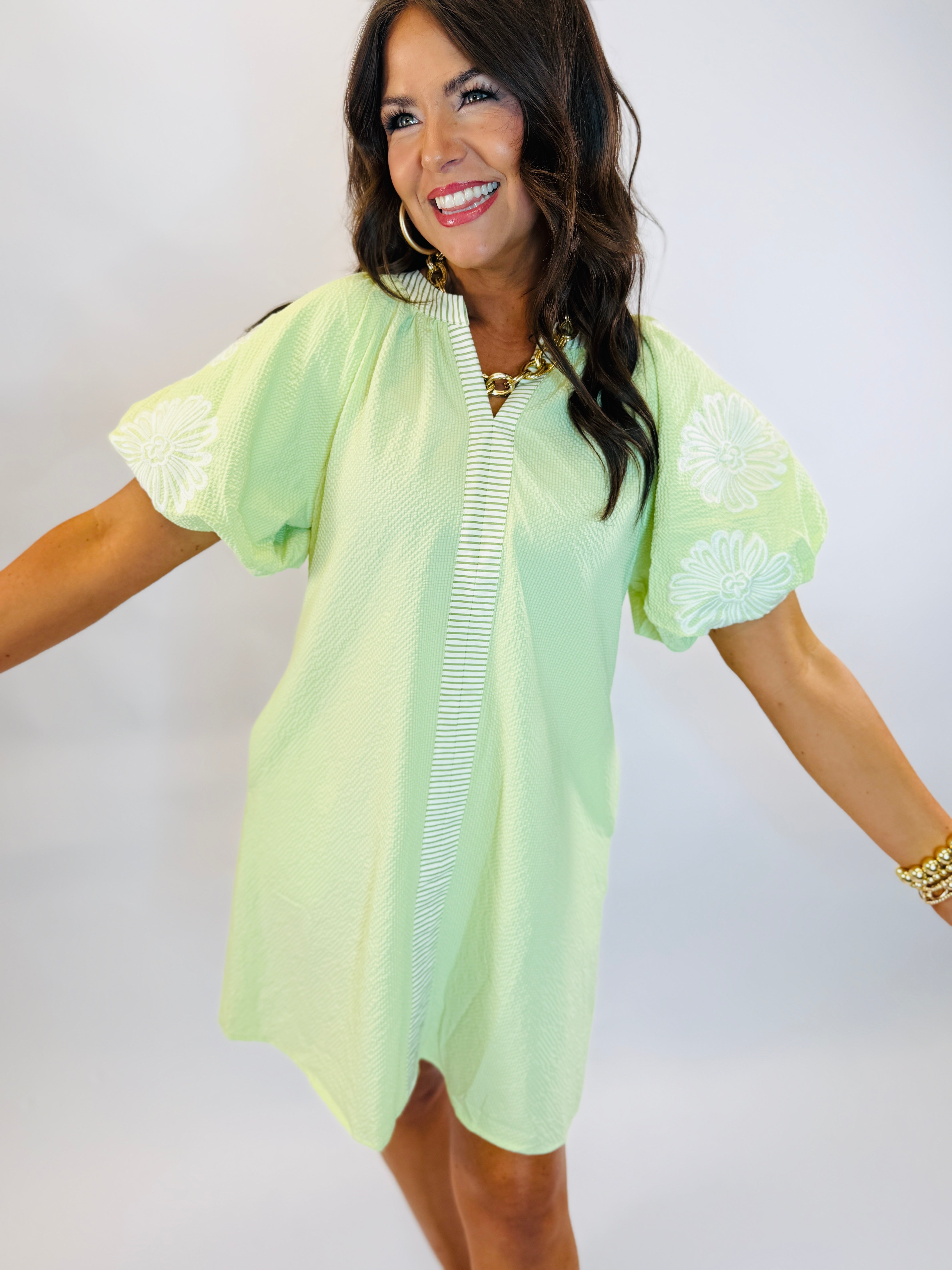 Woman wearing lime green Brielle dress with embroidered sleeves, white trim detail, and mock neck collar.