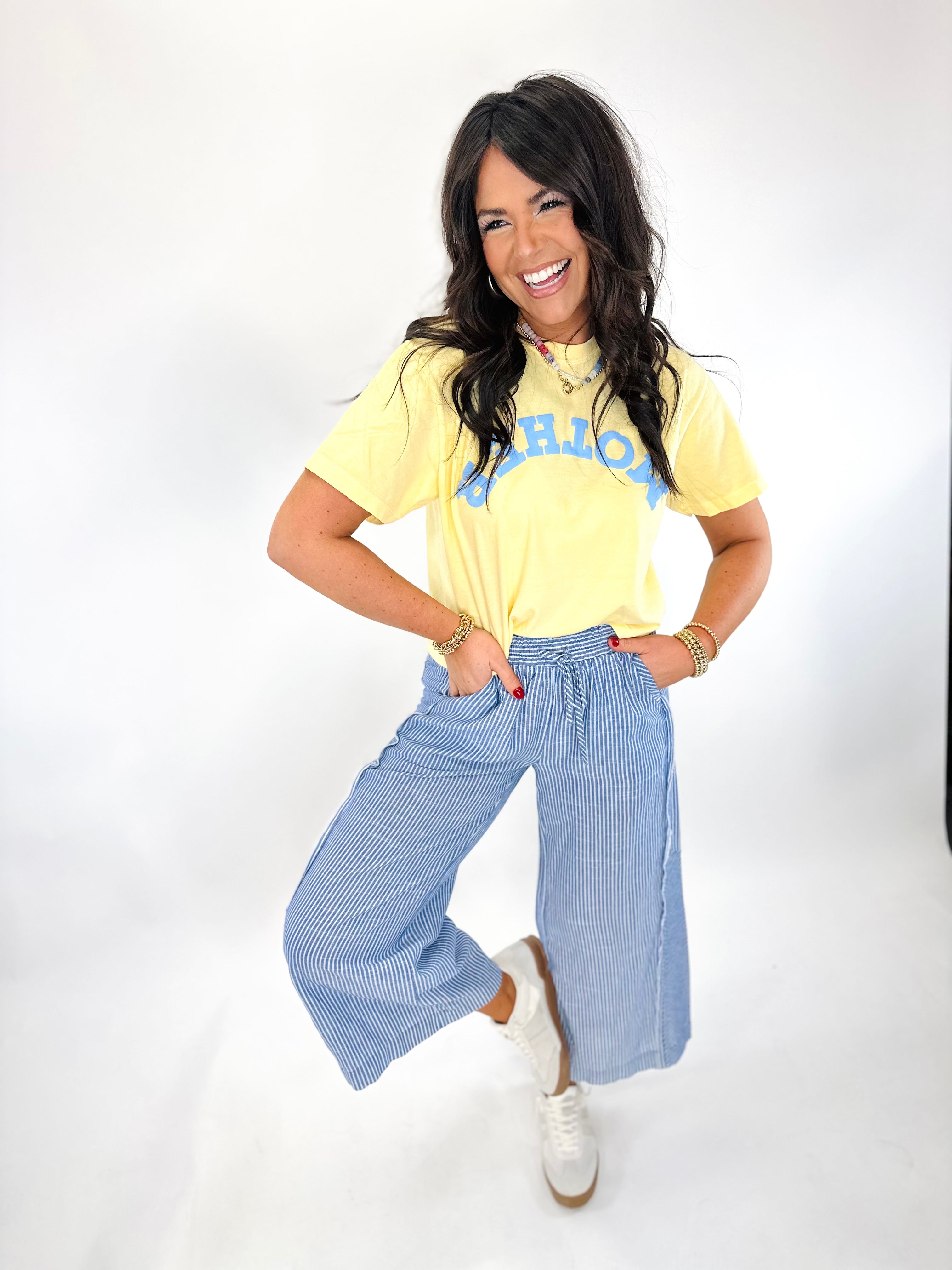 Woman wearing yellow graphic tee and blue striped wide-leg Delaney Breezy Pants with white sneakers