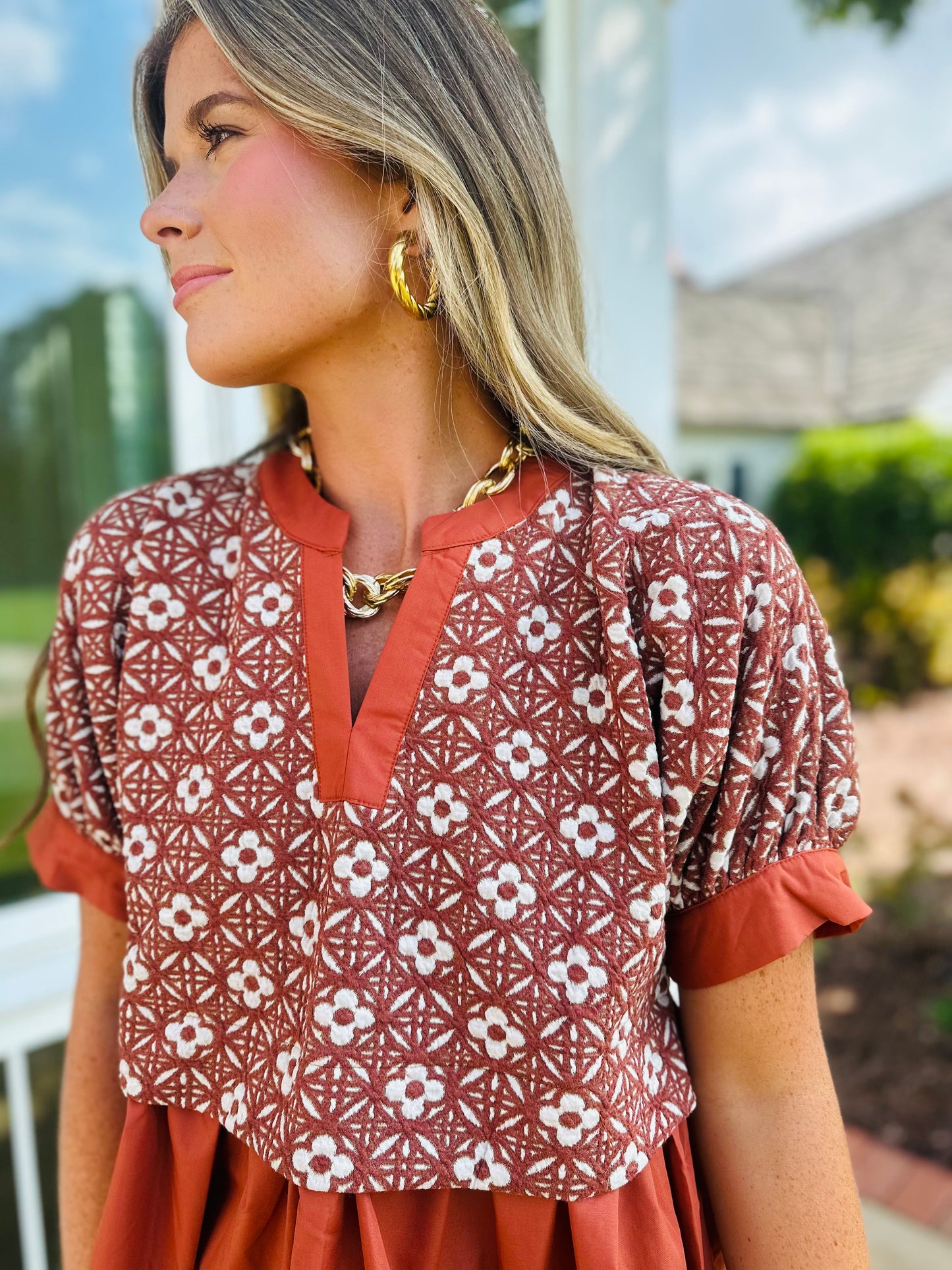 Woman wearing red patterned Alivia top with white floral print and contrasting solid trim details