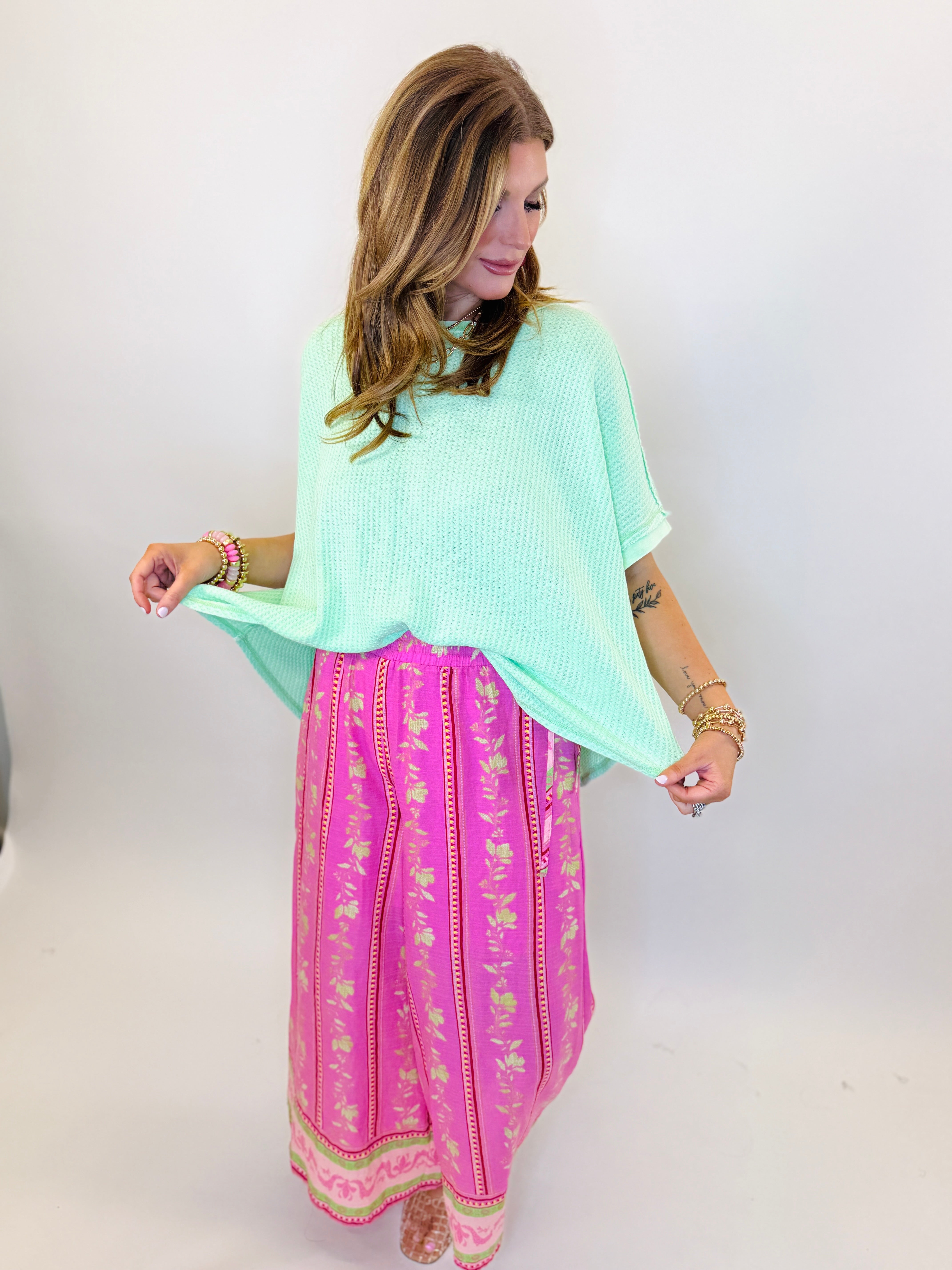 Woman wearing mint green oversized knit sweater with bell sleeves and pink patterned maxi skirt