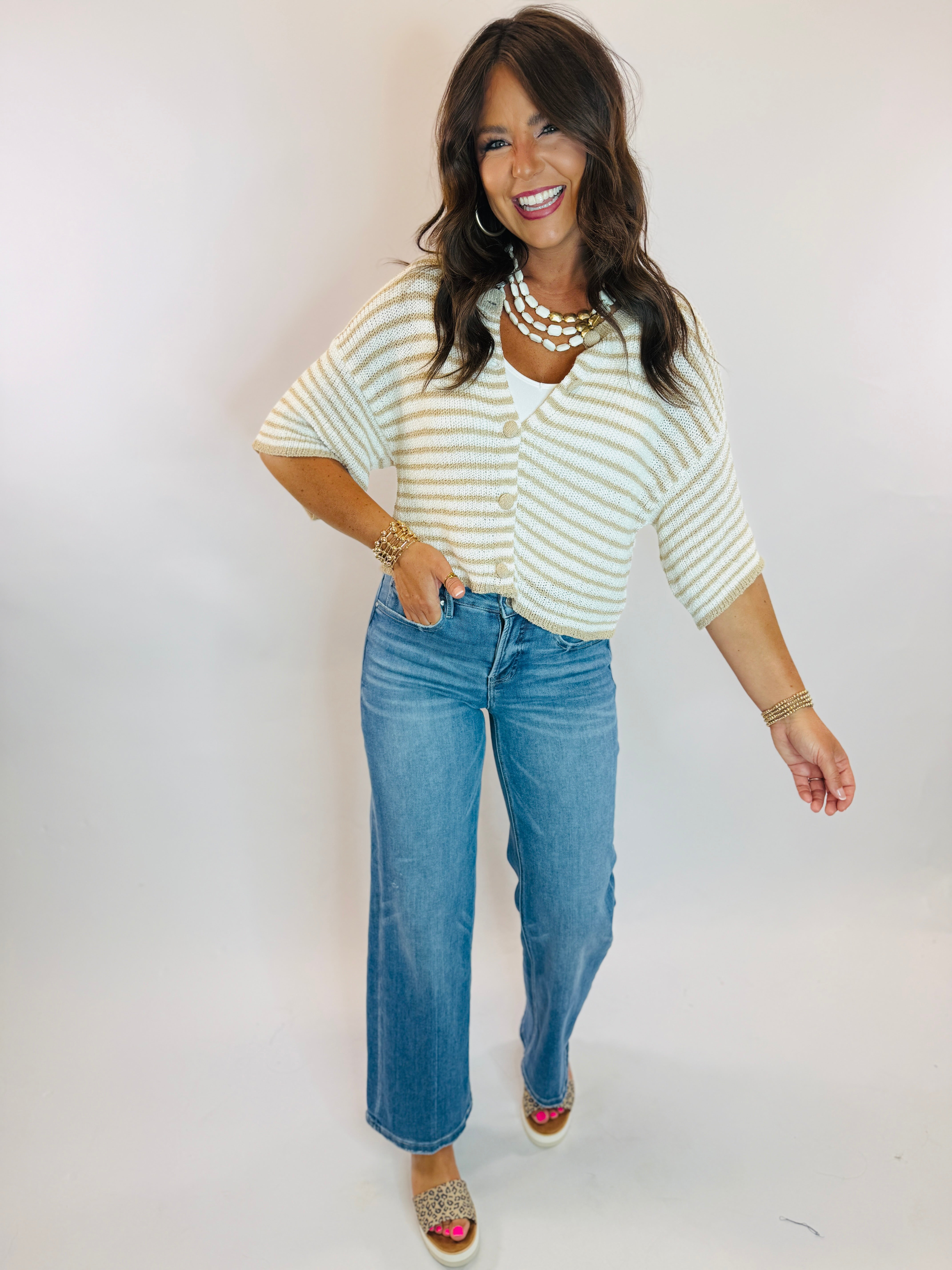 Woman wearing Vivian Top, a cropped cream and tan striped short-sleeve knit cardigan with gold buttons.