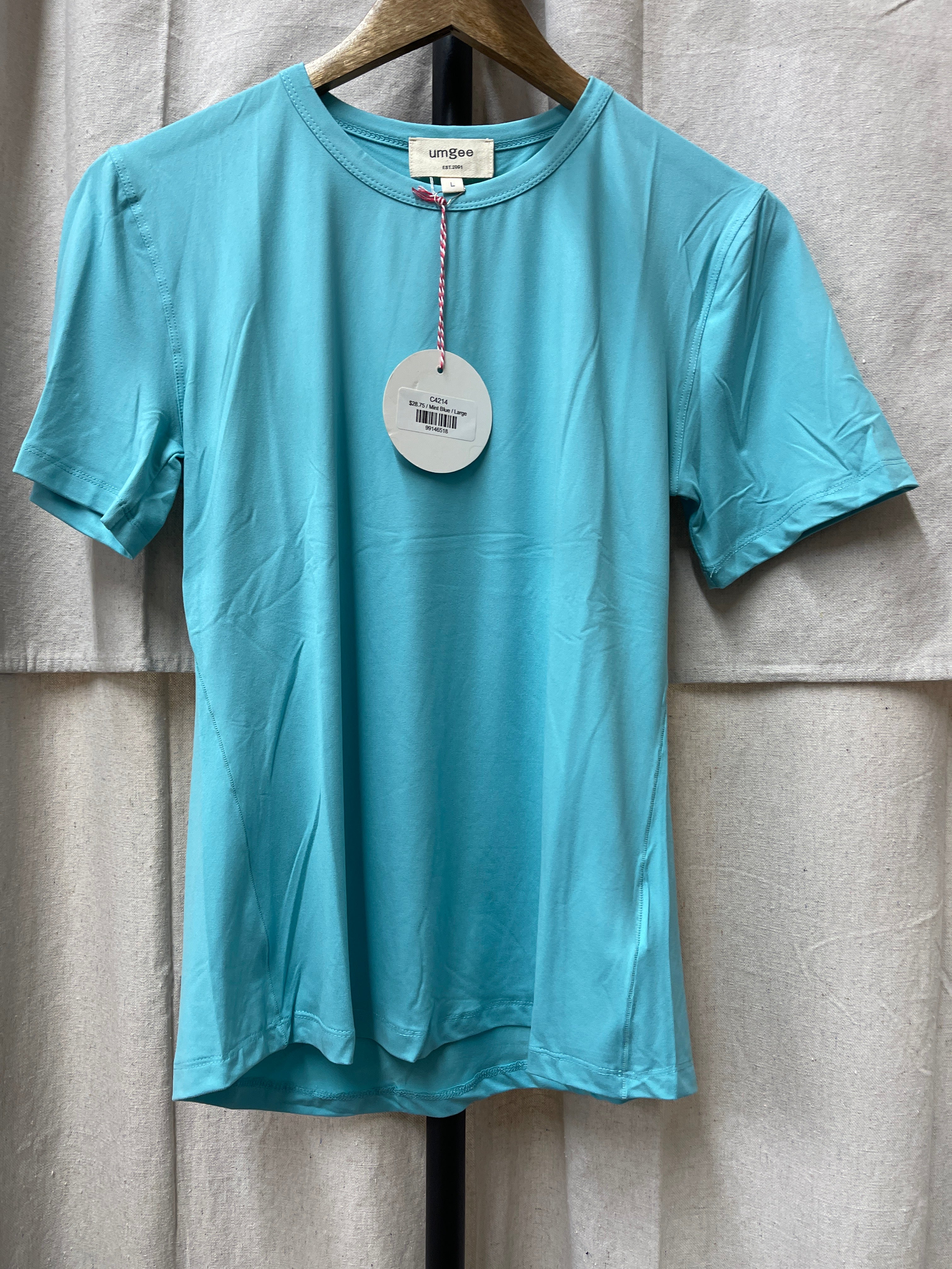Light blue Jenny Top by umgee hanging on wooden hanger with circular price tag attached.