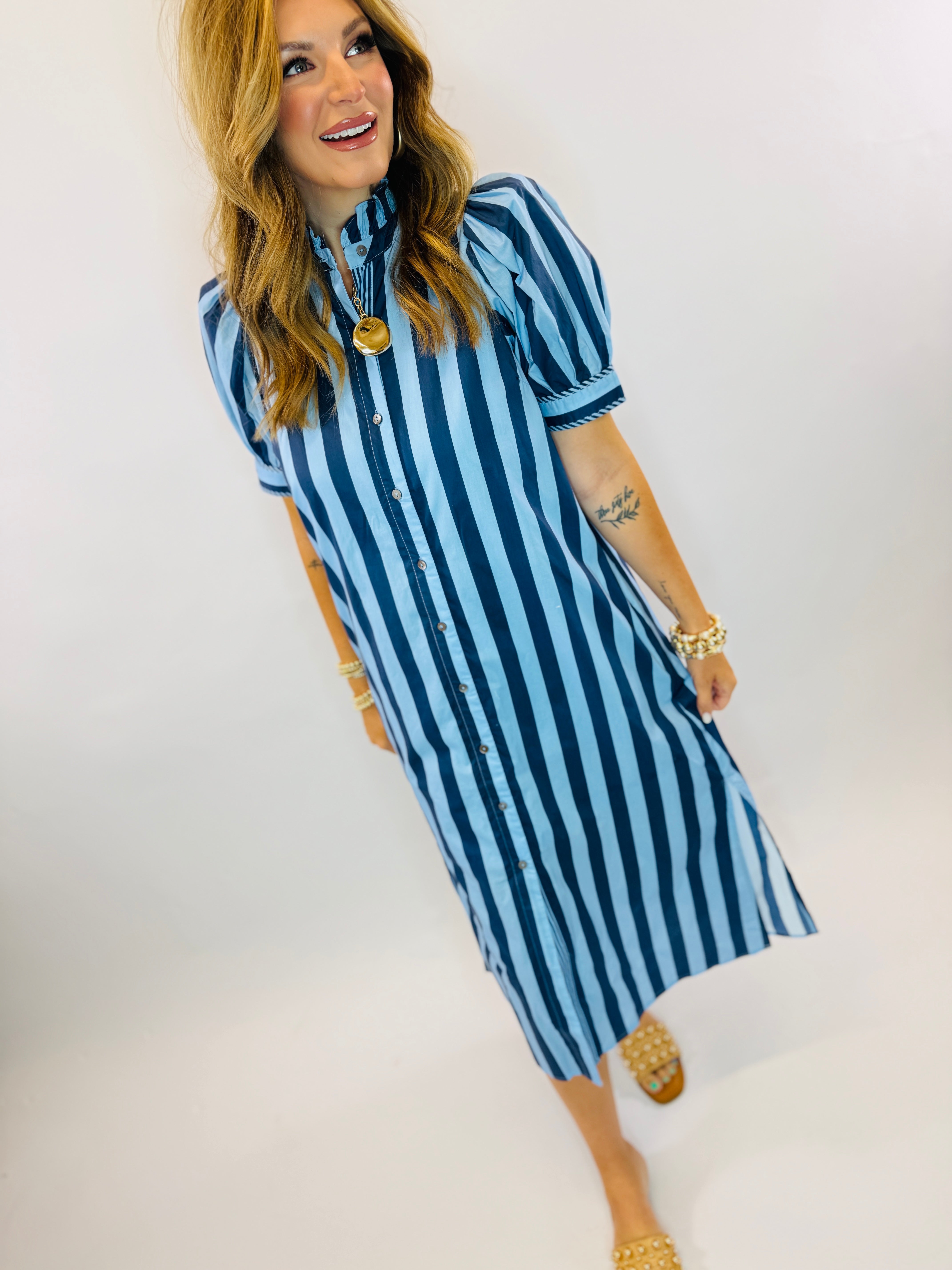 Woman wearing blue and white striped button-up maxi dress with short sleeves and collar.