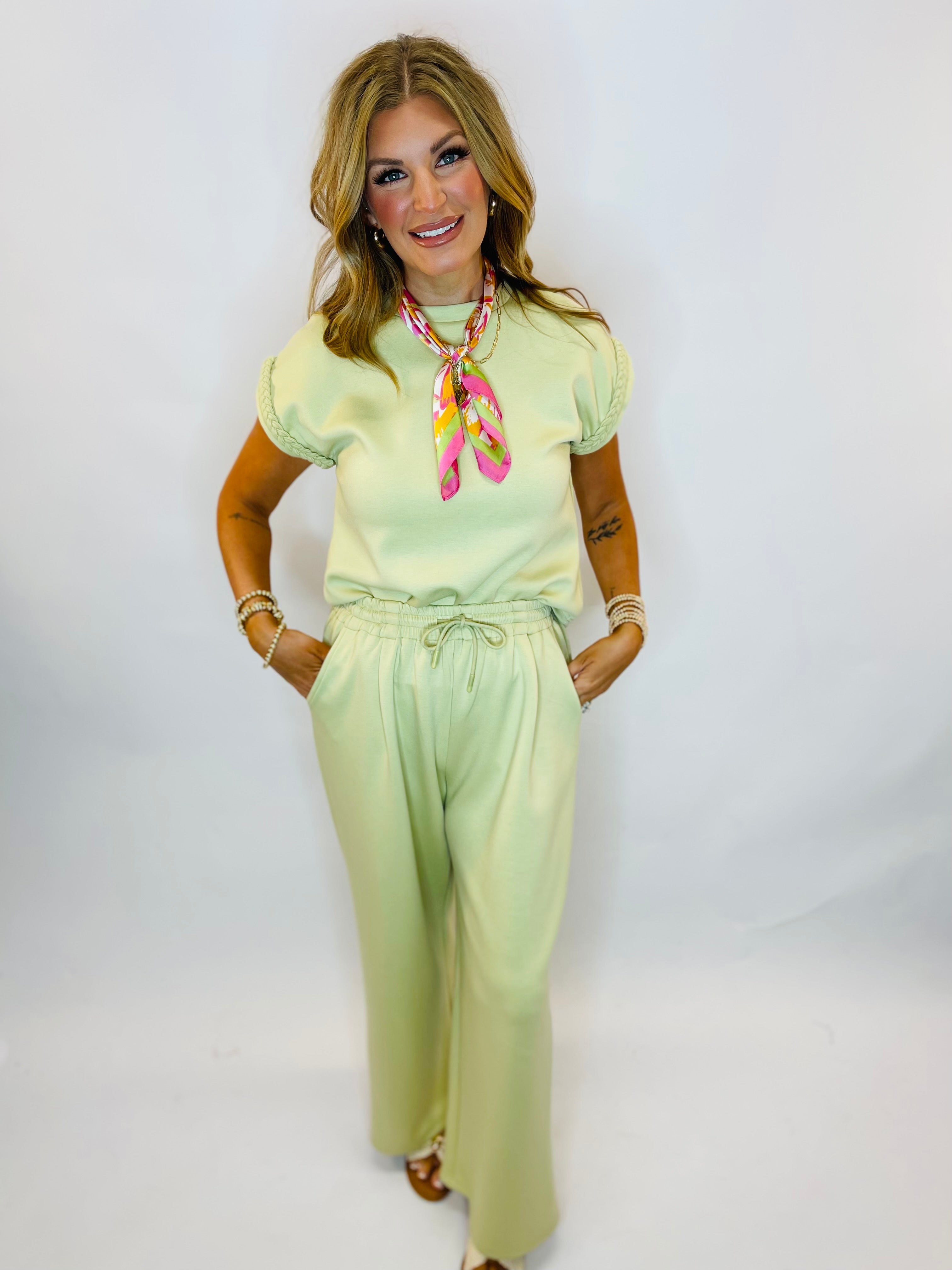 Woman wearing a mint green short sleeve top with braided sleeve detail and matching wide-leg pants set.