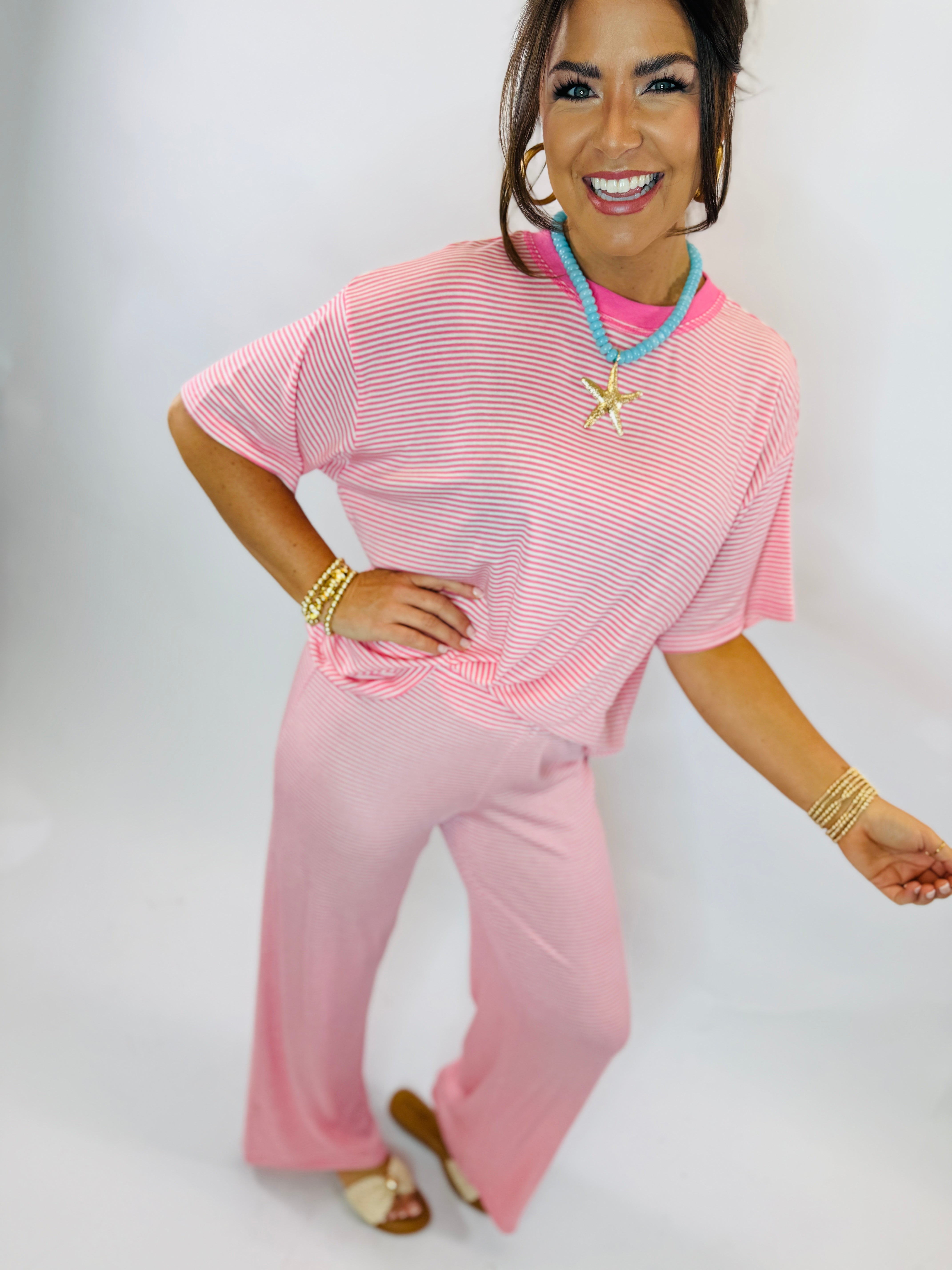 Woman wearing pink striped top and matching pink pants from Mita Set in Bubblegum Pink with turquoise necklace.