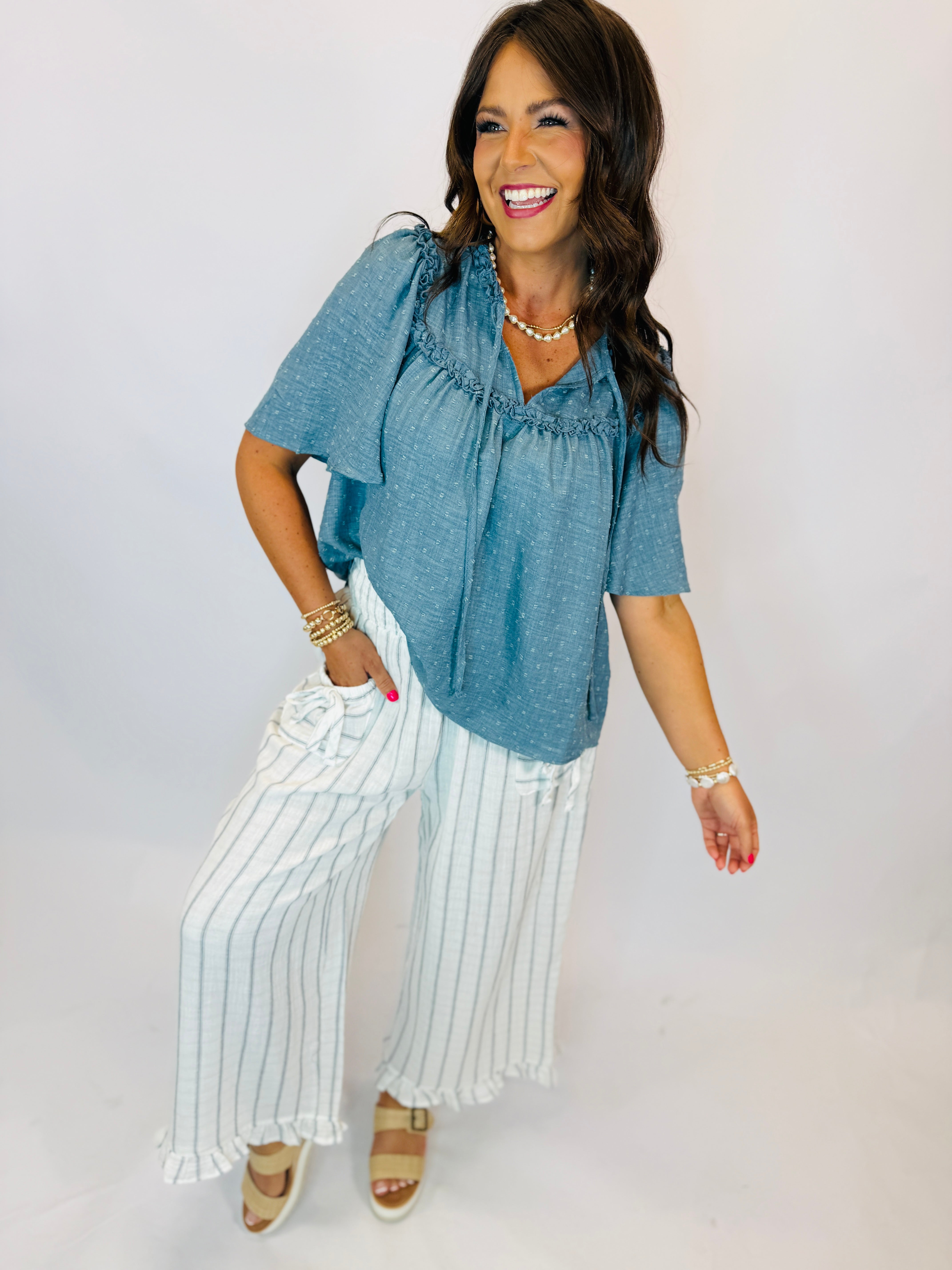 White and blue striped wide-leg pants with ruffled hem and pockets, styled with blue top.