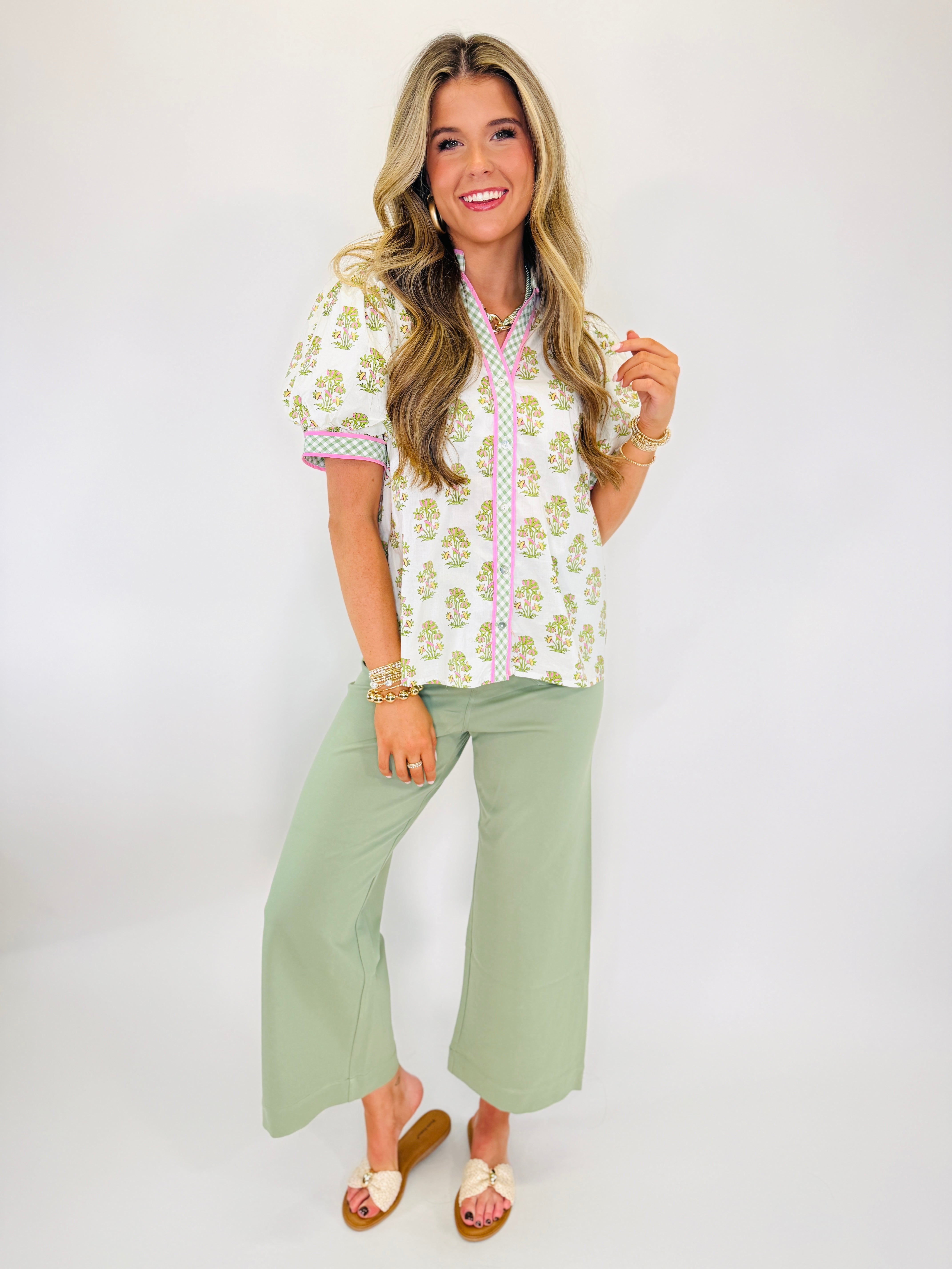 Woman wearing white Peyton soft knit top with green floral print and pink trim, paired with sage green pants.