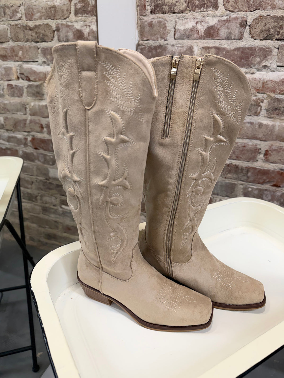 Jen Boot: tall beige suede cowboy boots with floral embroidery and gold side zipper.