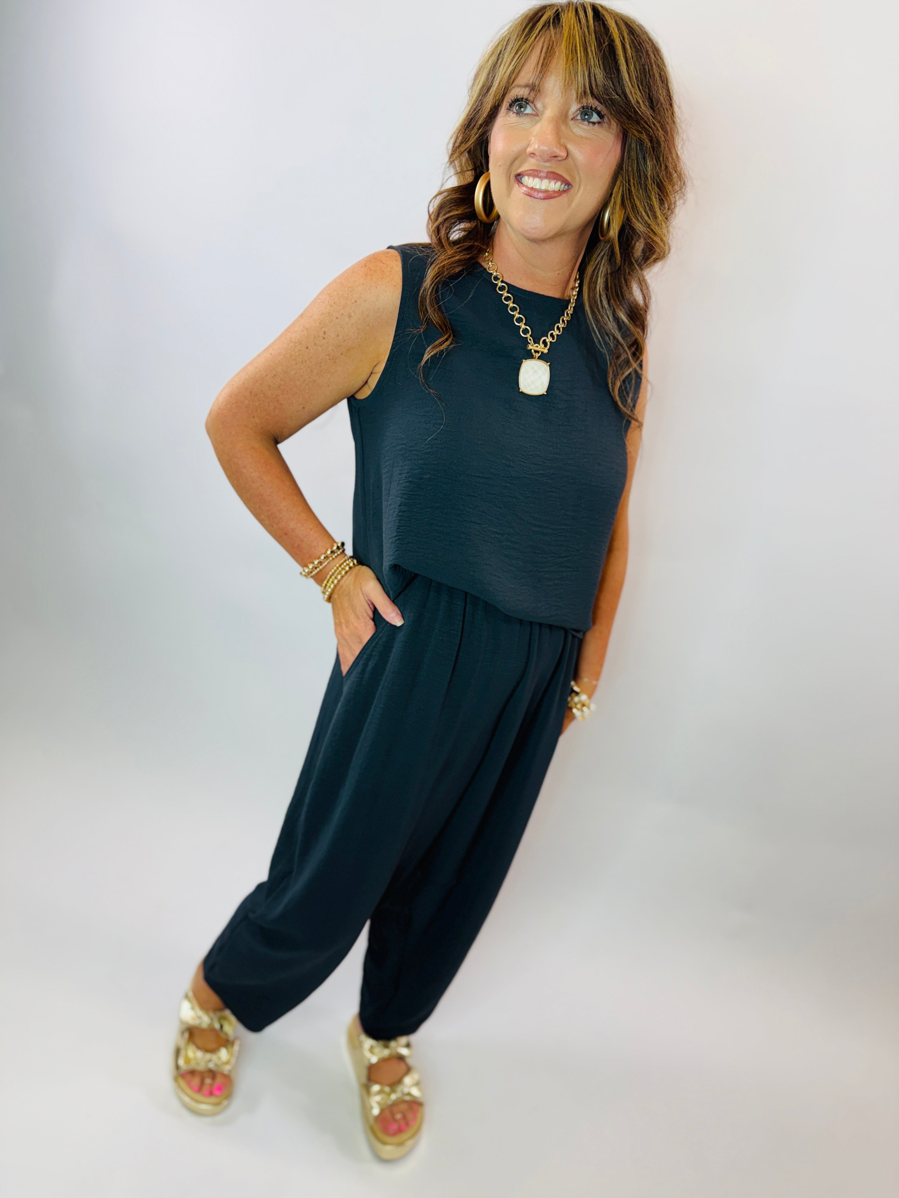 Woman wearing teal sleeveless top and matching wide-leg pants set, styled with gold jewelry and sandals.
