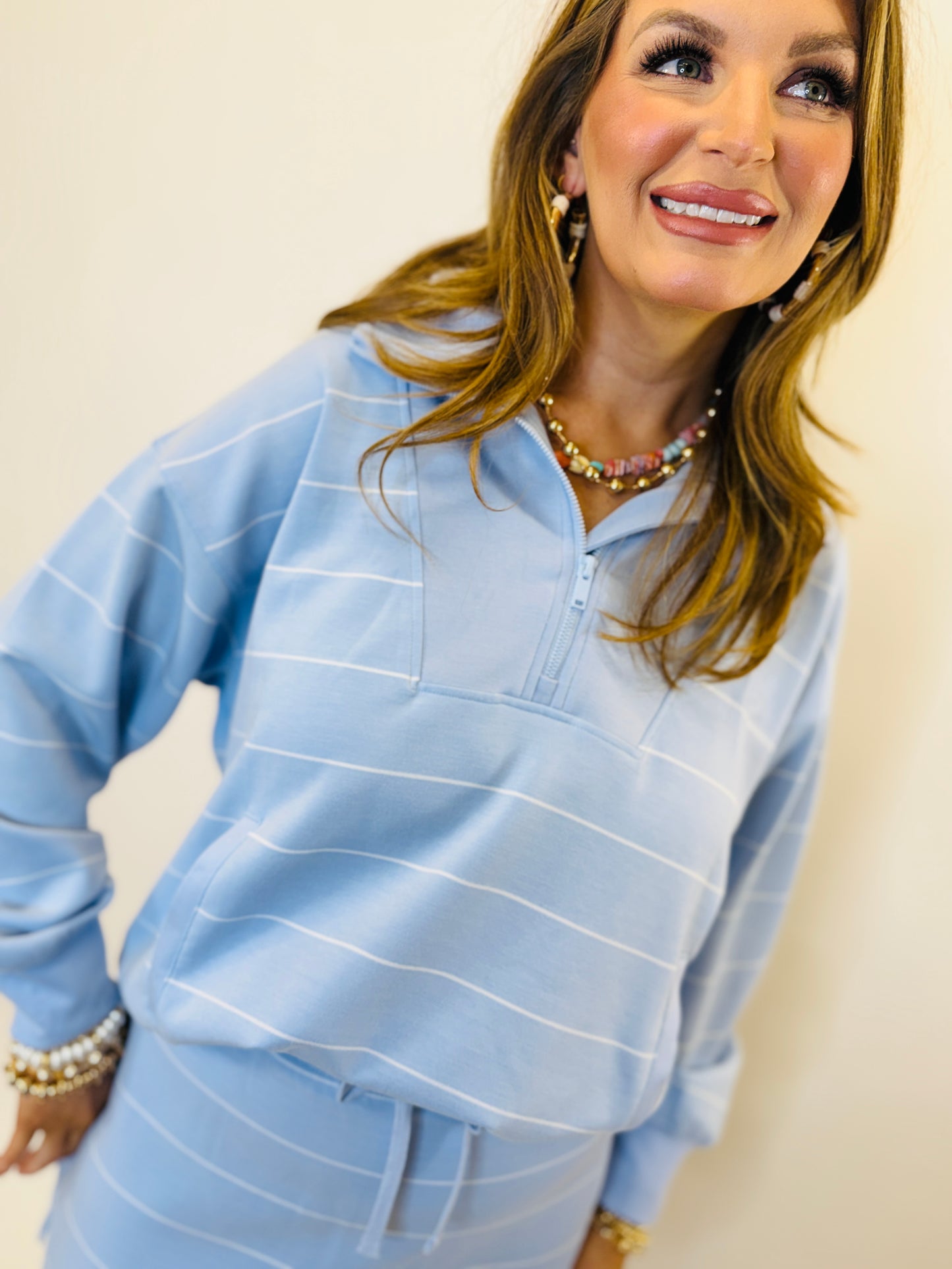Woman wearing light blue striped Briella lightweight pullover top with pearl jewelry and bracelet