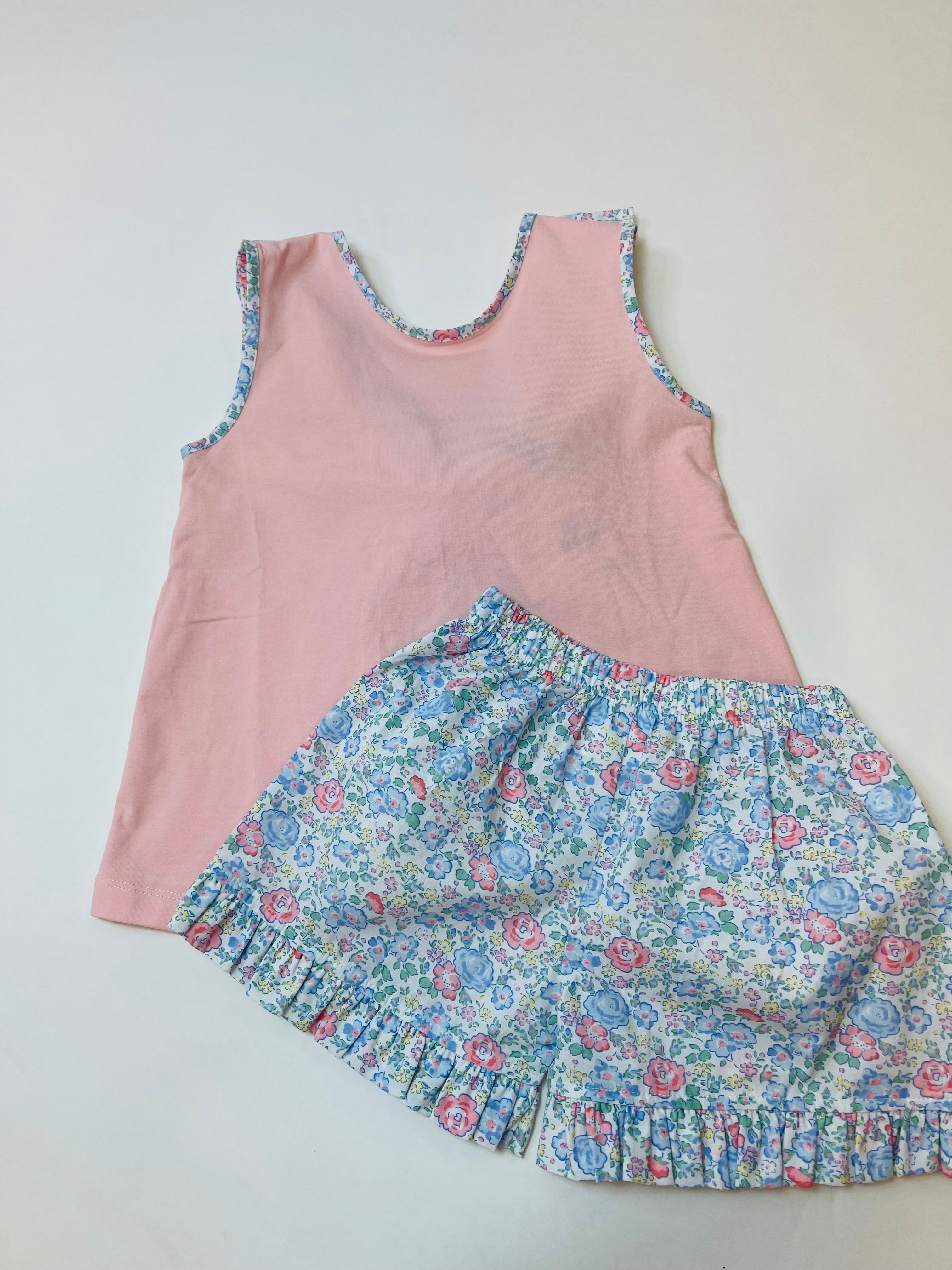 Pink sleeveless top with floral trim paired with matching blue floral ruffled shorts set for girls.