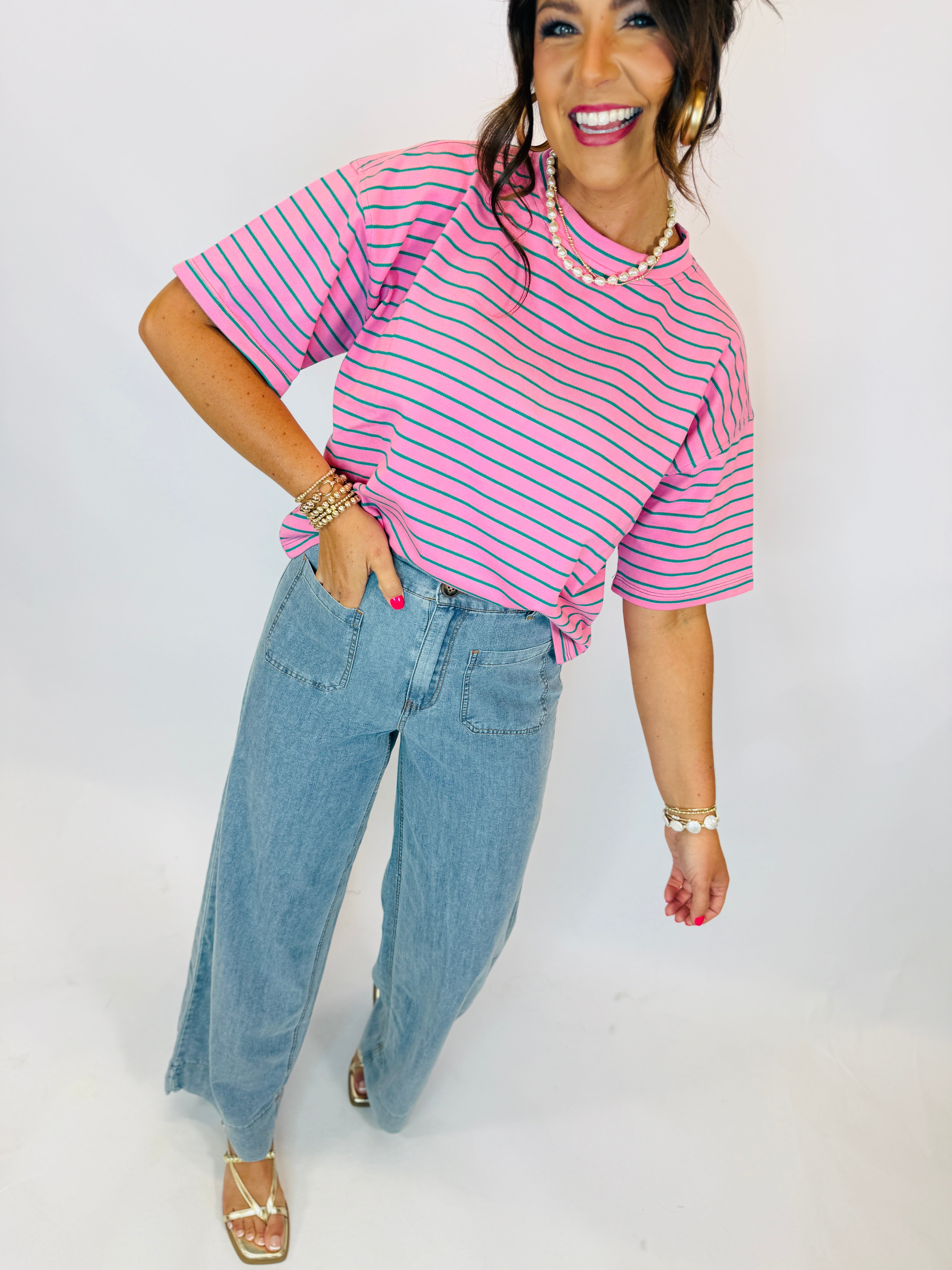 Woman wearing pink and green striped oversized cropped Taylor Top with light wash wide-leg jeans.