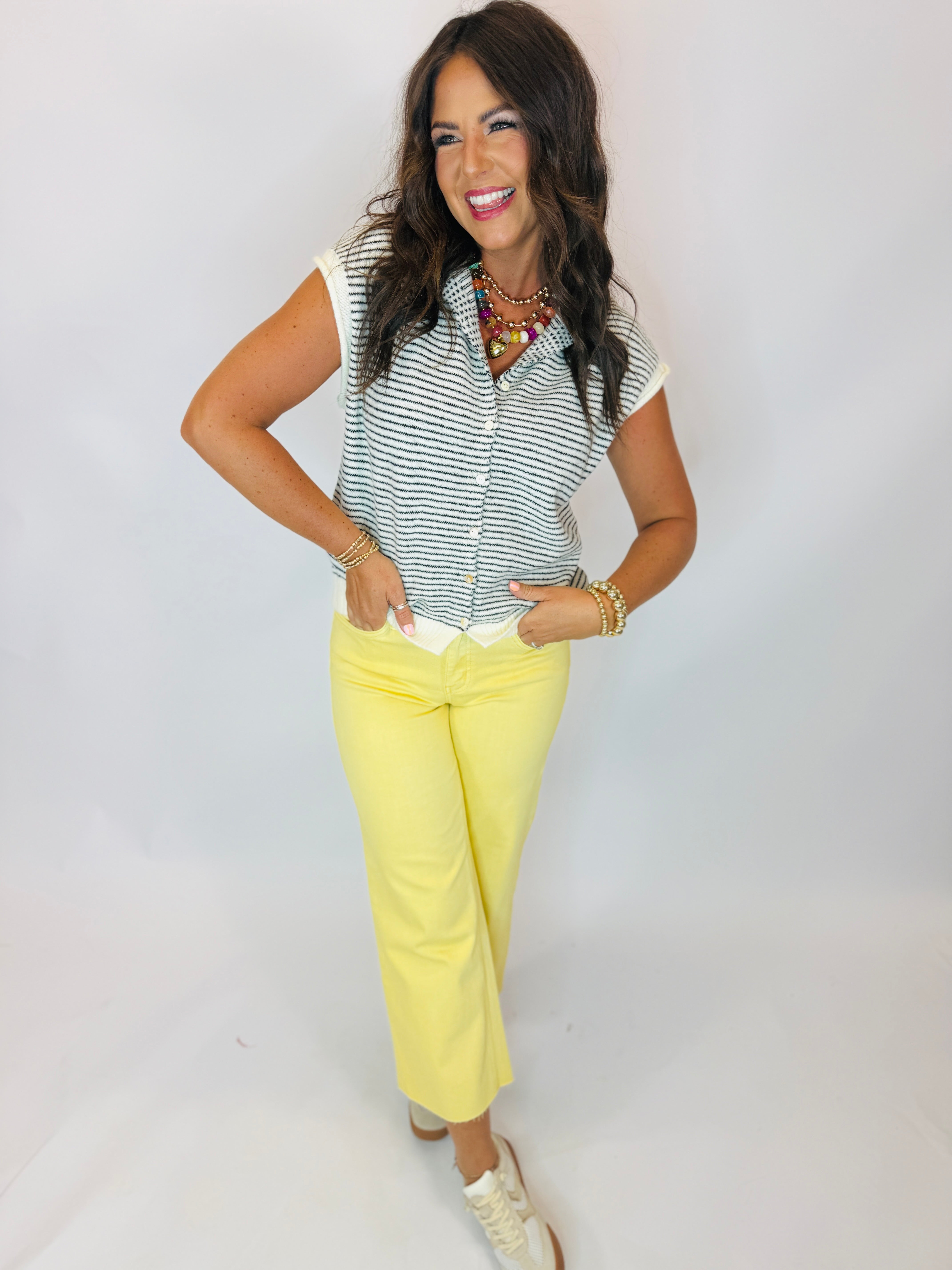 Woman wearing yellow wide-leg cropped Paige Jeans paired with striped sleeveless top and white sneakers.