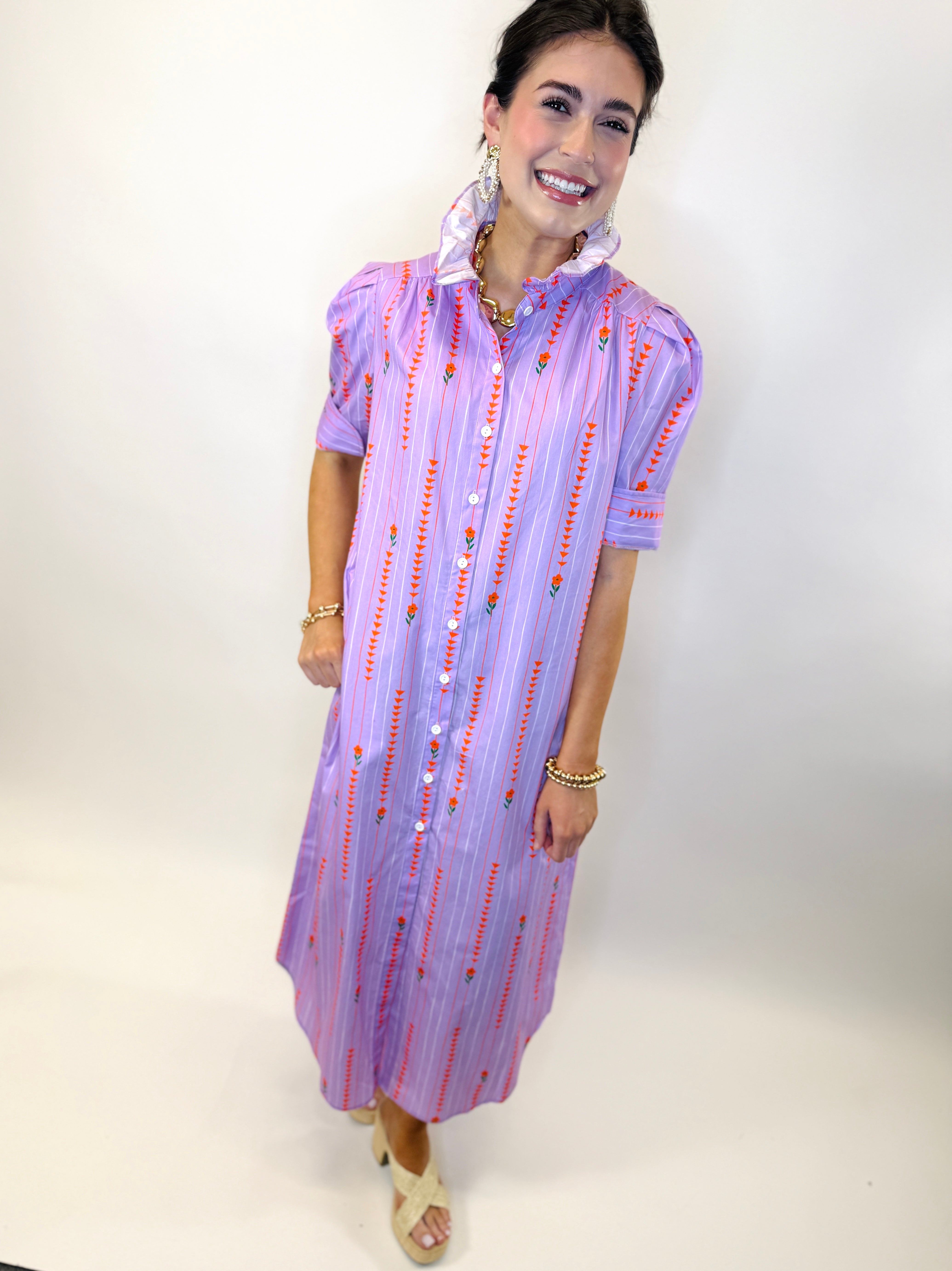 Woman wearing purple striped Nina dress with red embroidered details and white buttons, styled with gold jewelry.