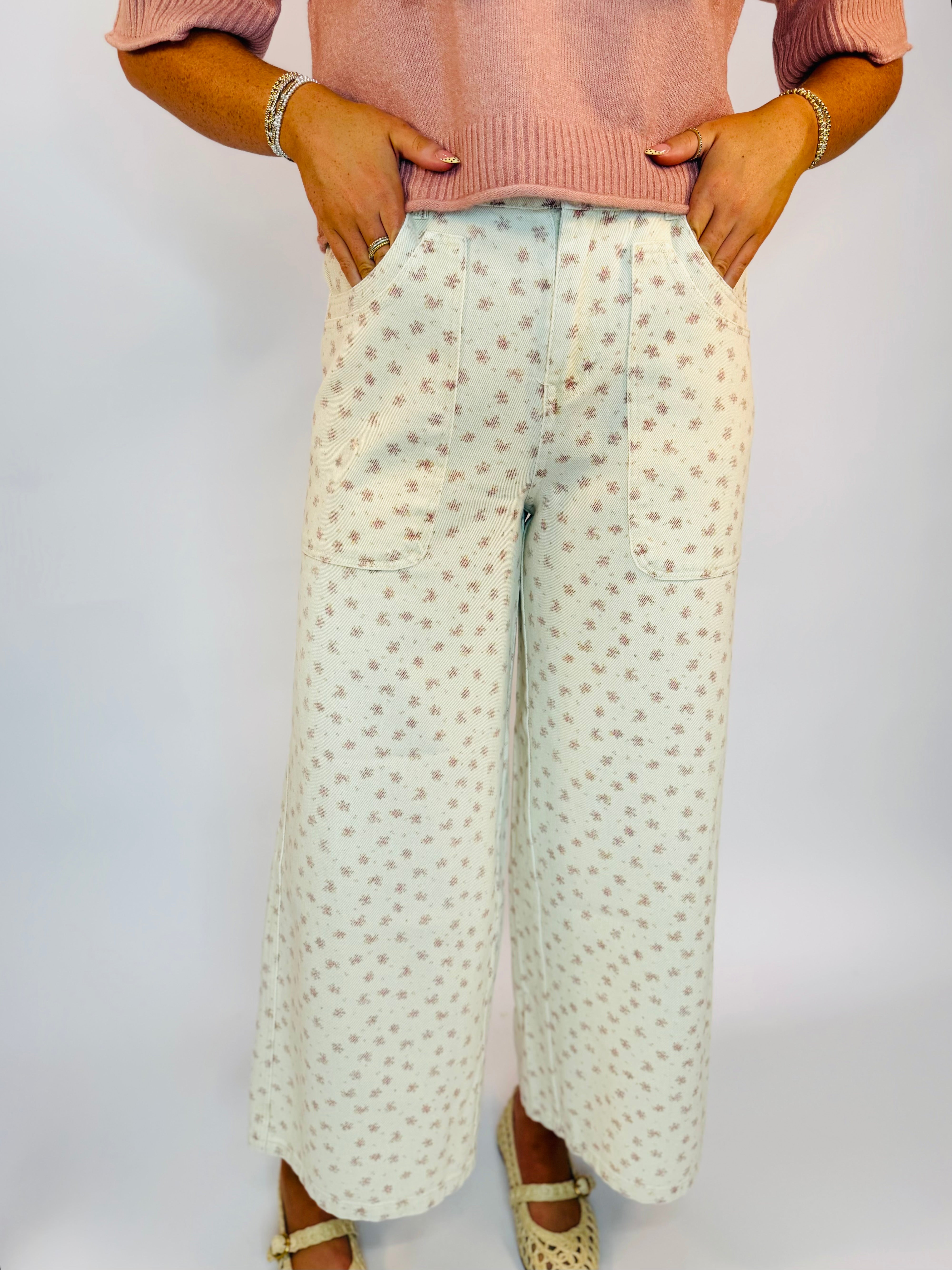 Wide-leg cream pants with pink floral print, patch pockets, styled with pink sweater and cream Mary Jane shoes.