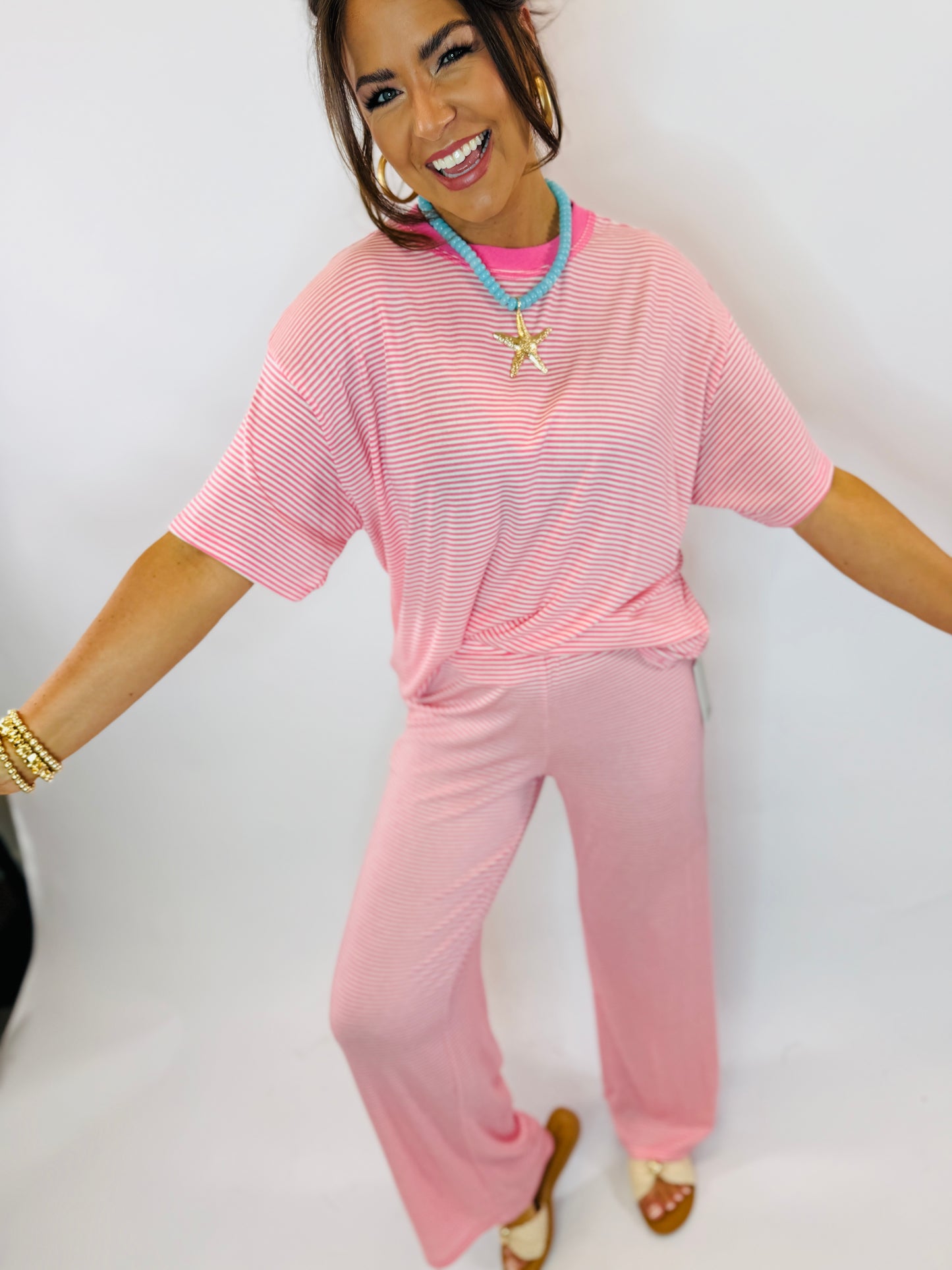 Woman wearing bubblegum pink striped top and matching wide-leg pants in a coordinated loungewear set