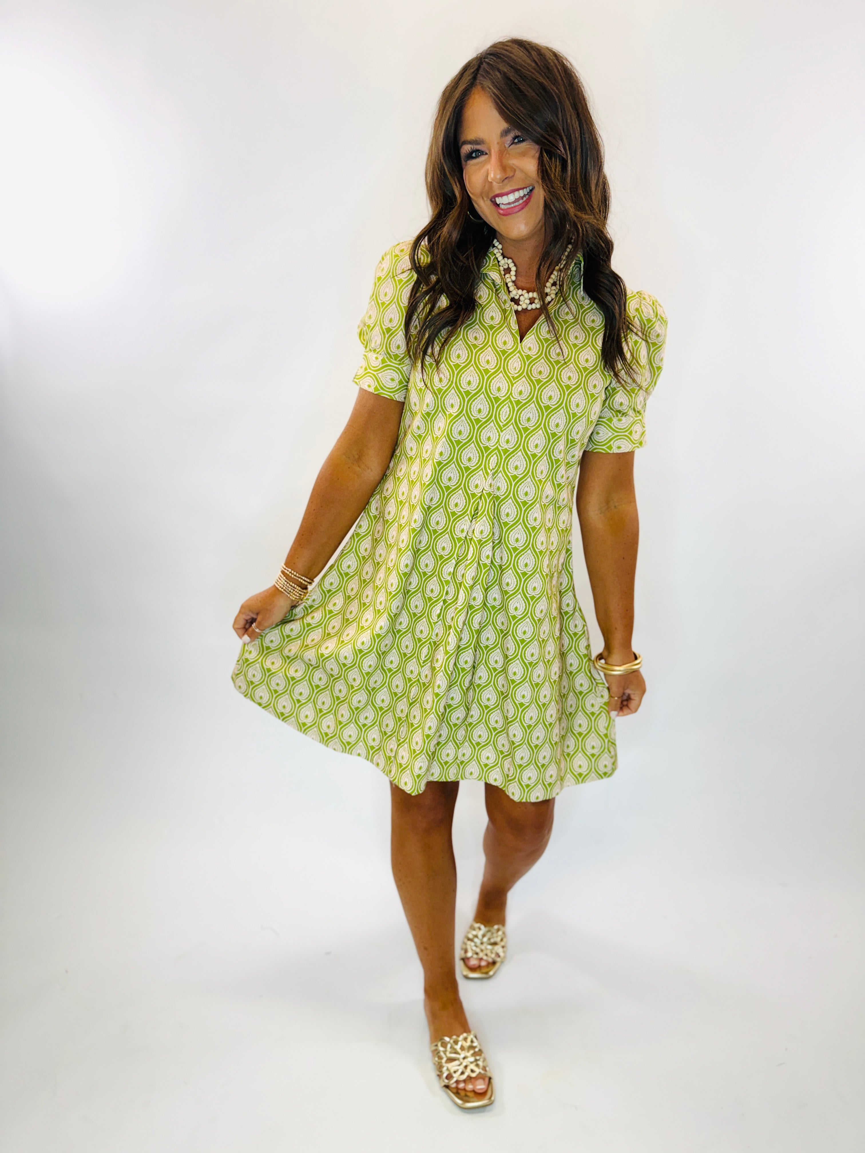 Woman wearing Lisa Dress in green and white teardrop print with puff sleeves and button front.