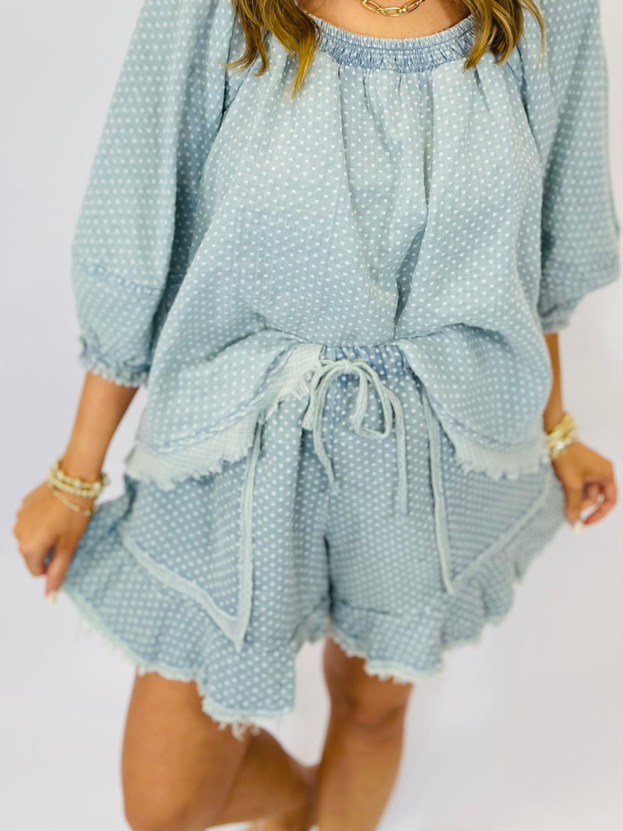 Light blue polka dot two-piece set with smocked top and drawstring shorts with frayed hem details.