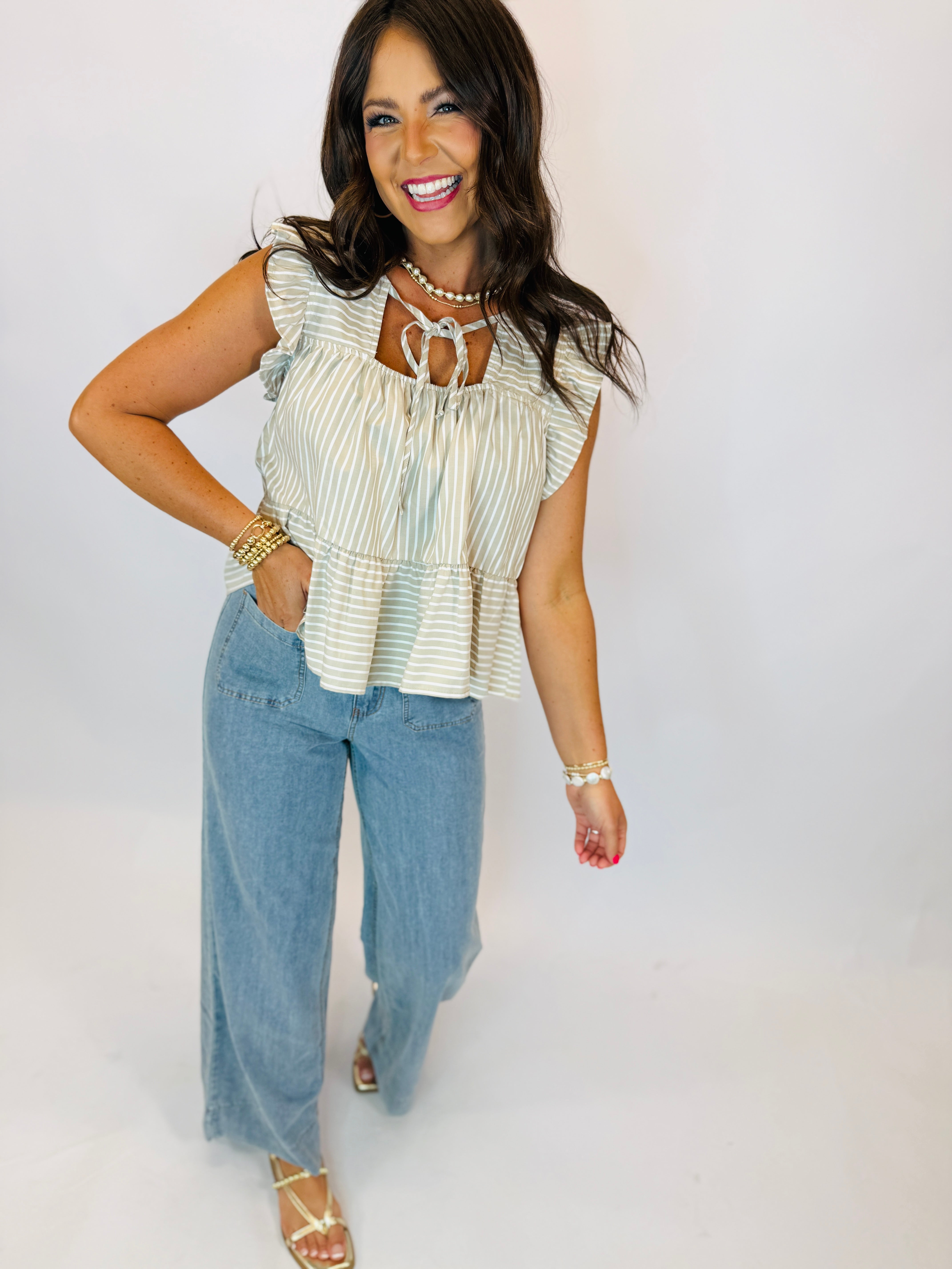 Woman wearing light wash wide-leg Brooke Pants paired with a striped ruffle top and gold sandals.